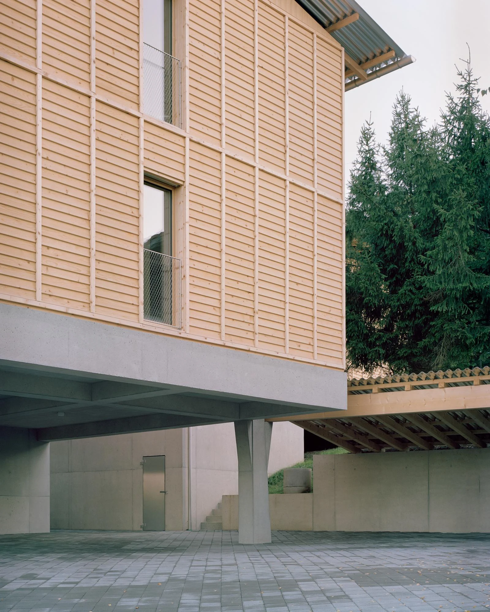 Hameau des Marais by Deschenaux Architectes — Courtepin, Switzerland: raw concrete pilotis and larch louvers holding spruce-lined dwellings in Fribourg.
