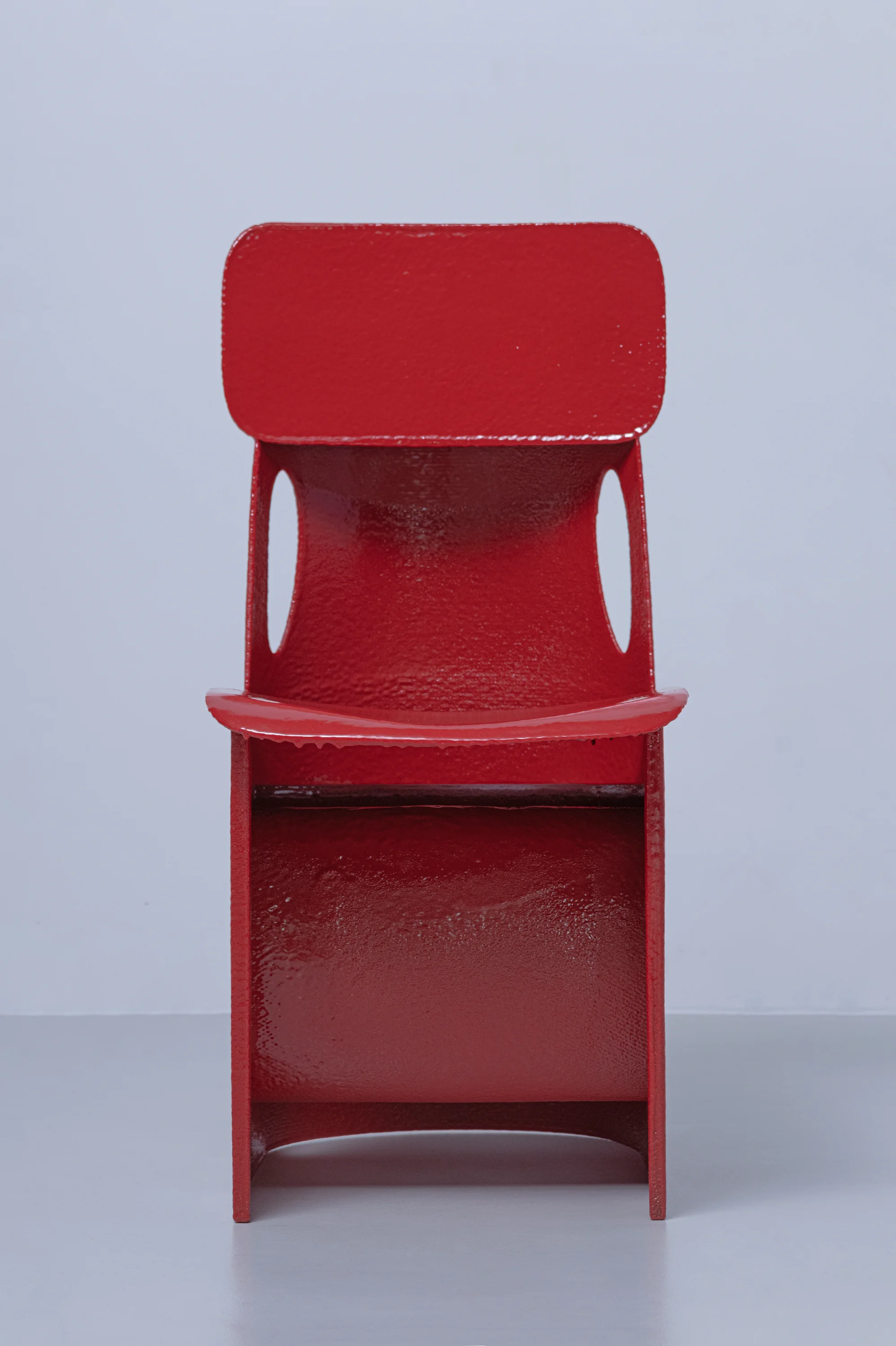 Hardened Mesh Project Chair 01 by Seongil Choi, photographed by Sangpil Lee — Rear view showing the continuous back and base as a single folded plane, the two large oval voids framing the grey surface behind them.