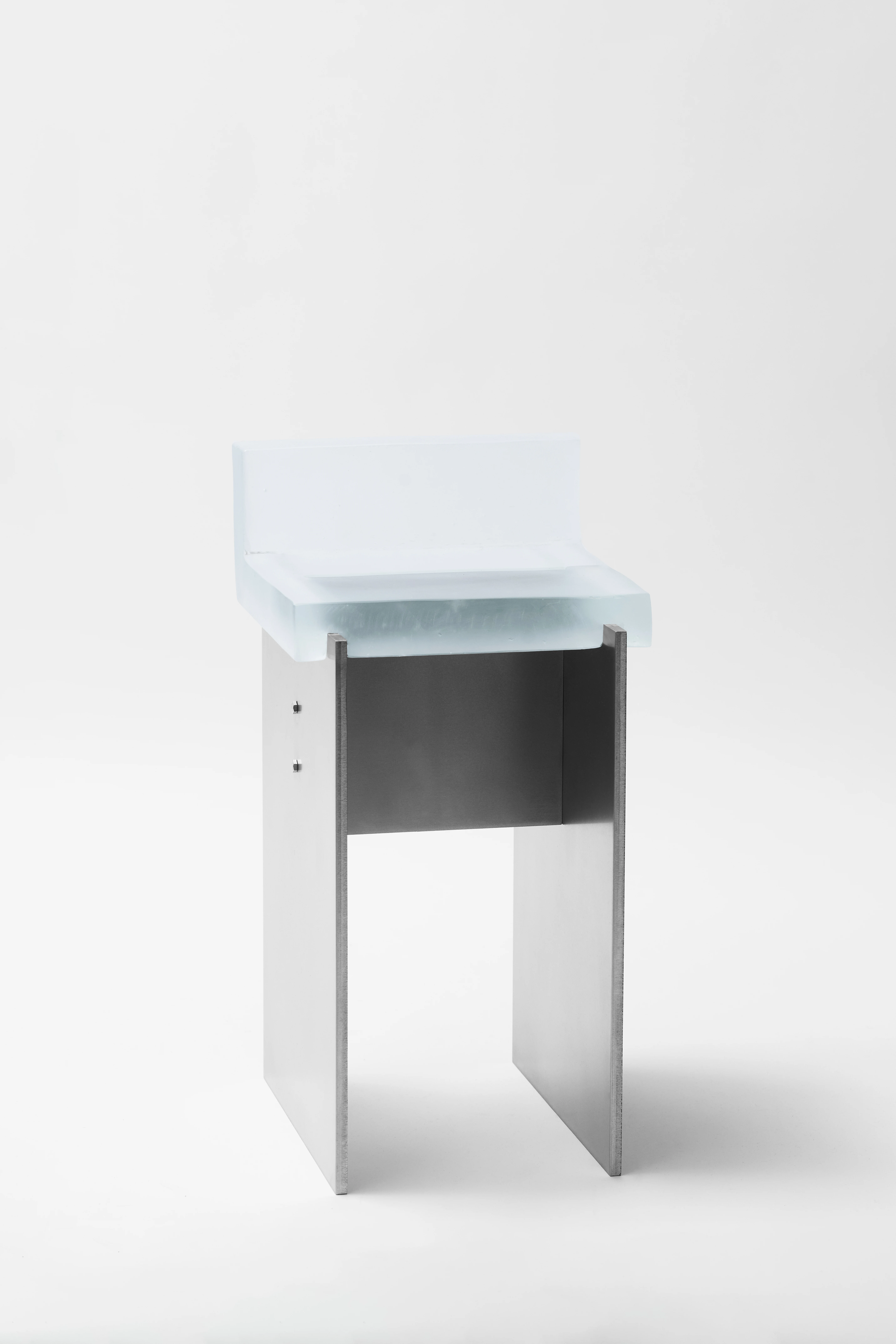 Rest Chair by Obscure Objects, Studio Maximilian Beck, photographed by Konstantin Walther, Maximilian Beck — Front elevation of Rest Chair, the flat stainless steel back panel dominating with the pale glass seat visible only at the top edge, hex bolt…