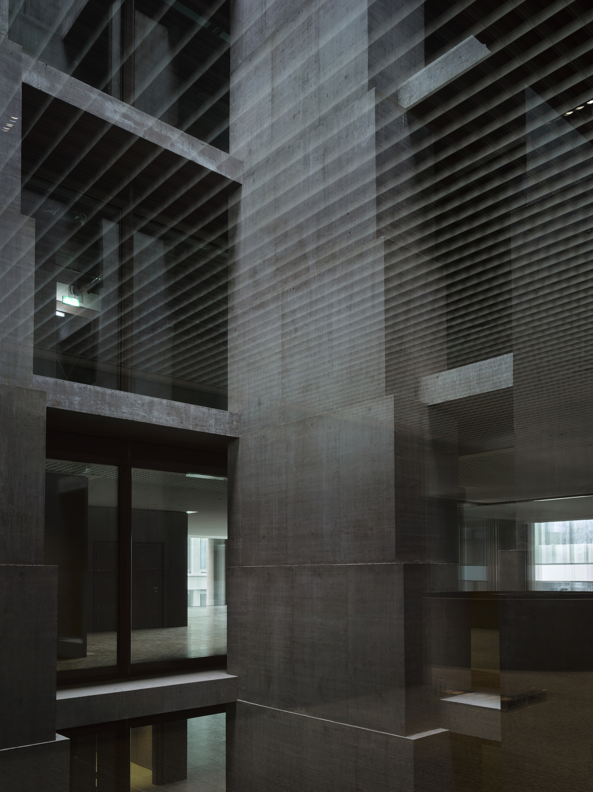 Baloise Insurance Company Office Tower by Valerio Olgiati, photographed by Bas Princen — Central atrium rises through multiple floors, horizontal metal louvers creating striations against the concrete columns.
