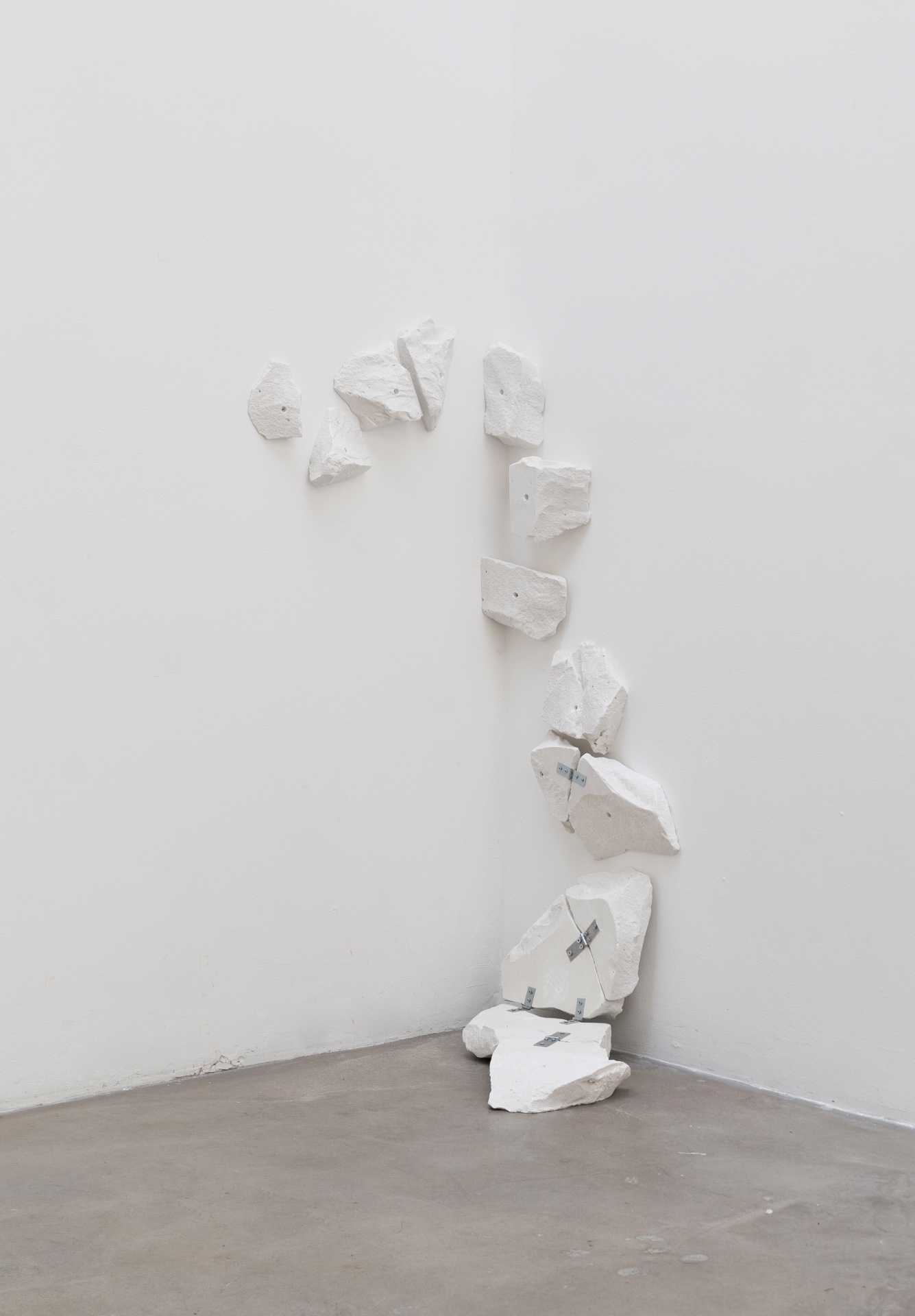 Main de fer, gant de velours by Agurto + Fiedler, photographed by Katherinne Fiedler — Serpentin by Marinés Agurto, reclaimed plaster blocks cascading down gallery corner, zinc hinges linking irregular white fragments from wall to floor.