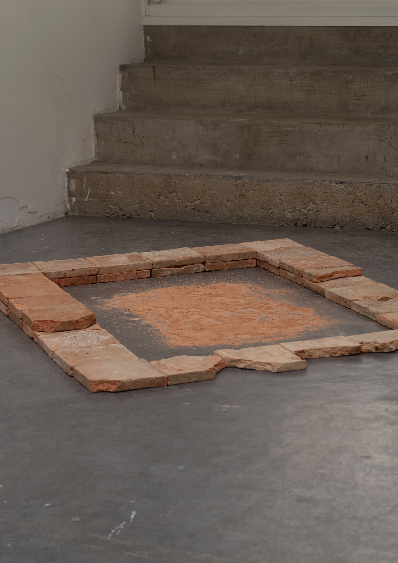 Main de fer, gant de velours by Agurto + Fiedler, photographed by Katherinne Fiedler — Huaka I by Marinés Agurto, recovered terracotta tiles framing rectangle of ochre pigment on polished concrete floor near stone steps.