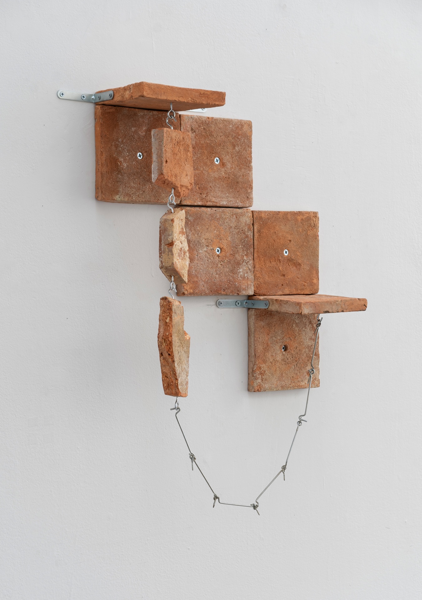 Main de fer, gant de velours by Agurto + Fiedler, photographed by Katherinne Fiedler — Bedrock by Marinés Agurto, recovered terracotta tomettes assembled on wall with zinc brackets, eyebolts, and looping wire connecting fragments.