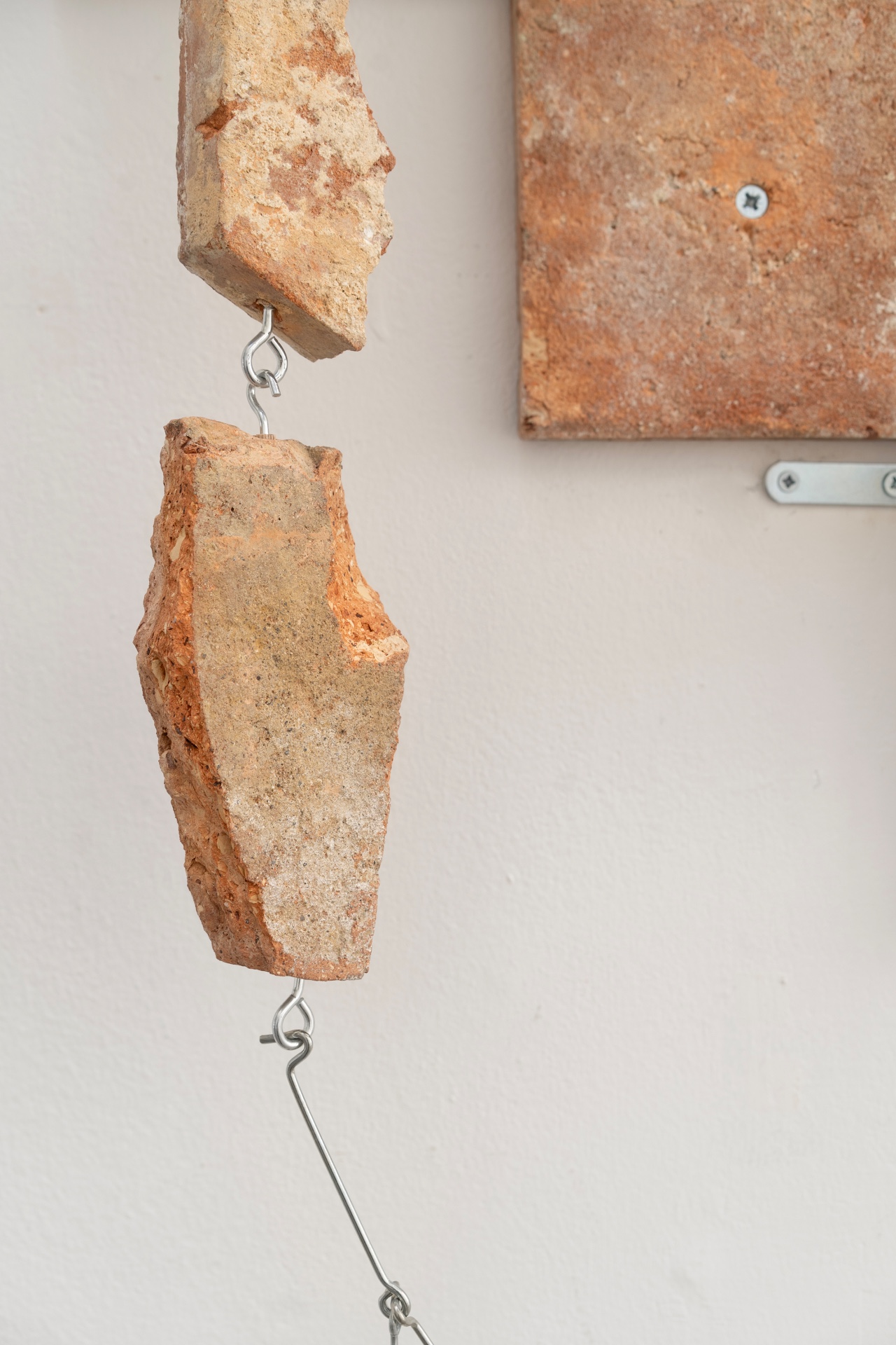 Main de fer, gant de velours by Agurto + Fiedler, photographed by Katherinne Fiedler — Bedrock detail, rust-orange terracotta fragments connected by wire threaded through eyebolts, weathered tile surfaces visible.