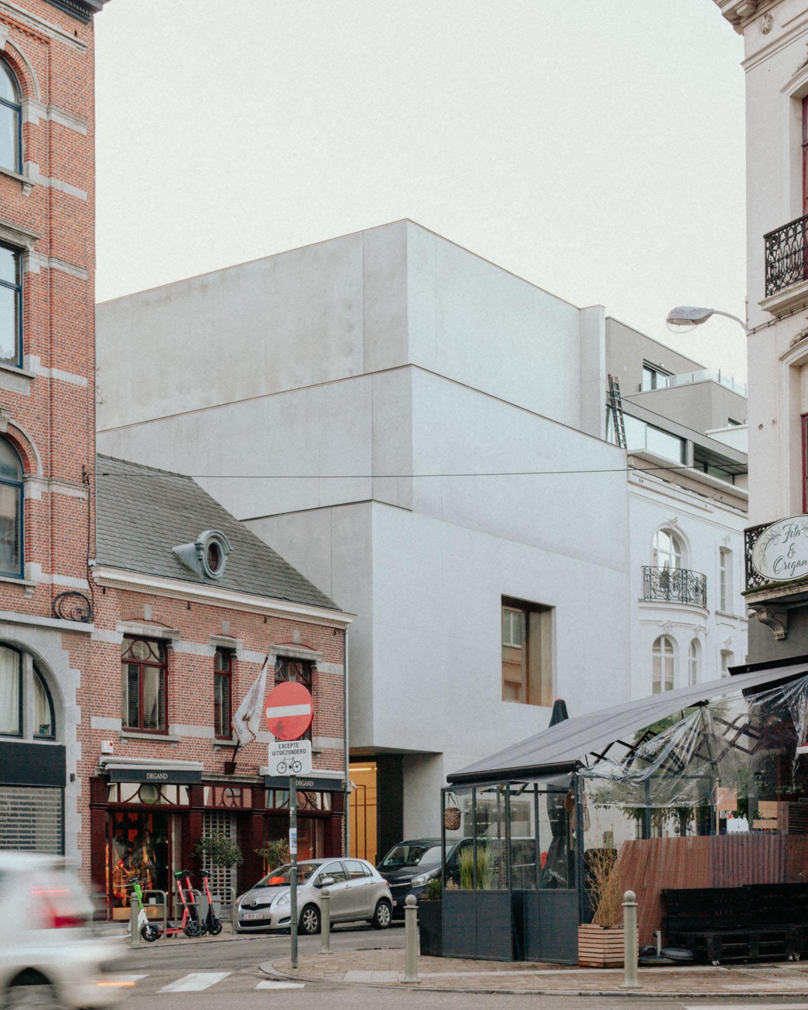 Xavier Hufkens Gallery by Robbrecht en Daem Architecten, photographed by Jeremy Piret — Street view of the stacked concrete extension rising above Brussels storefronts, cascade massing against nineteenth-century brick neighbors.