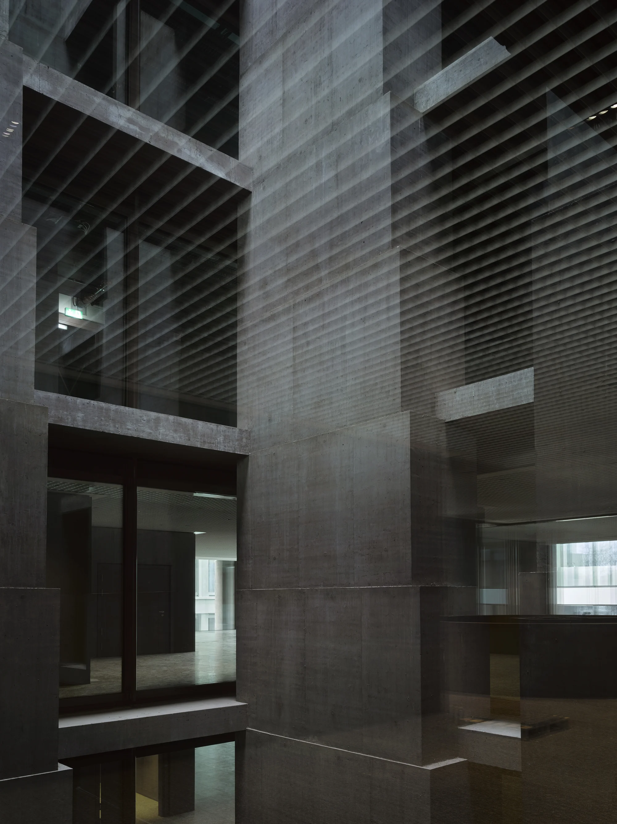 Baloise Insurance Company Office Tower by Valerio Olgiati, photographed by Bas Princen — Central atrium rises through multiple floors, horizontal metal louvers creating striations against the concrete columns.