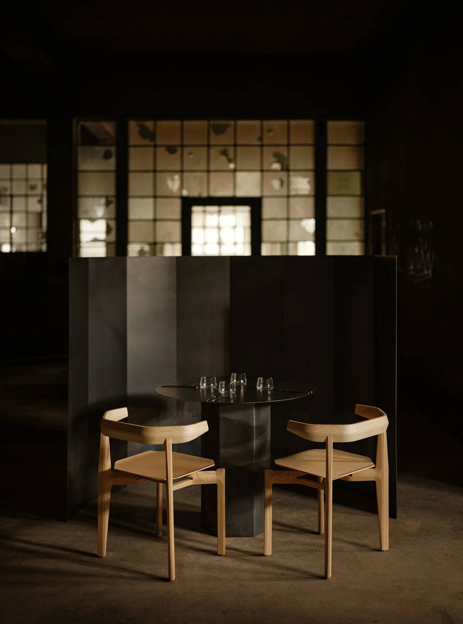 Rasa Collection by Carlos Pereira, photographed by Paulo Carvalho — Detail view of a dark stained Rasa chair: the bent single-plank backrest, the square-section leg joints, and the upholstered seat cushion are visible together, the joinery logic of the…