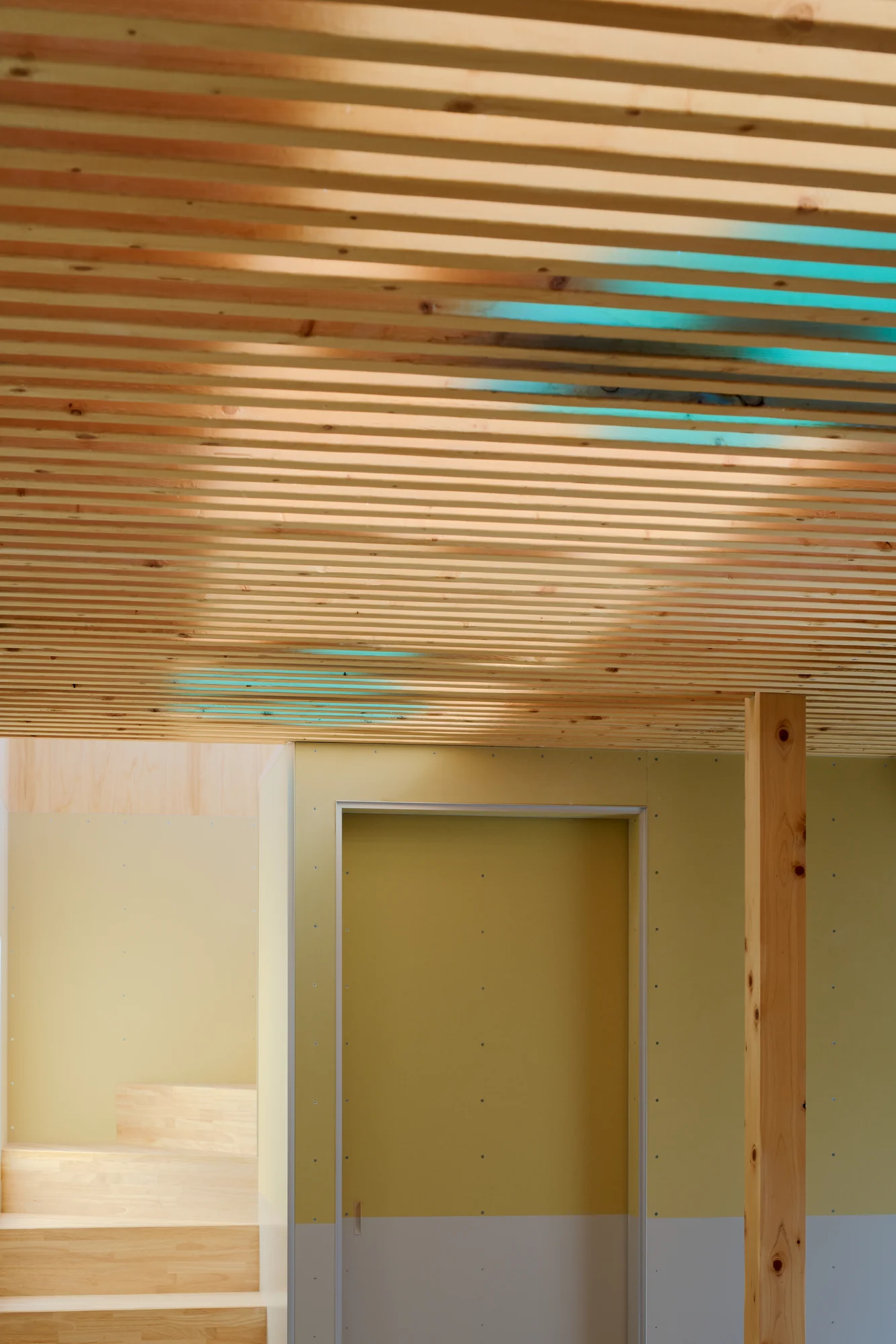 House TN by 1-1 Architects, photographed by Takashi Uemura — Detail of the louver ceiling with blue polycarbonate panels visible between timber slats, staircase leading to the upper level.