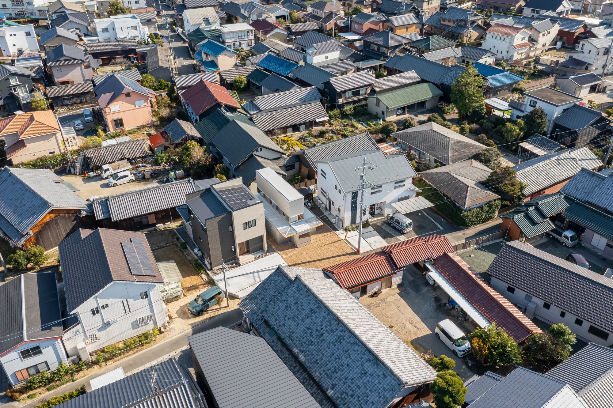 House TN by 1-1 Architects, photographed by Takashi Uemura — Aerial view reveals House TN's corrugated metal roof and terrace within the dense fabric of Anjo's mixed residential blocks.