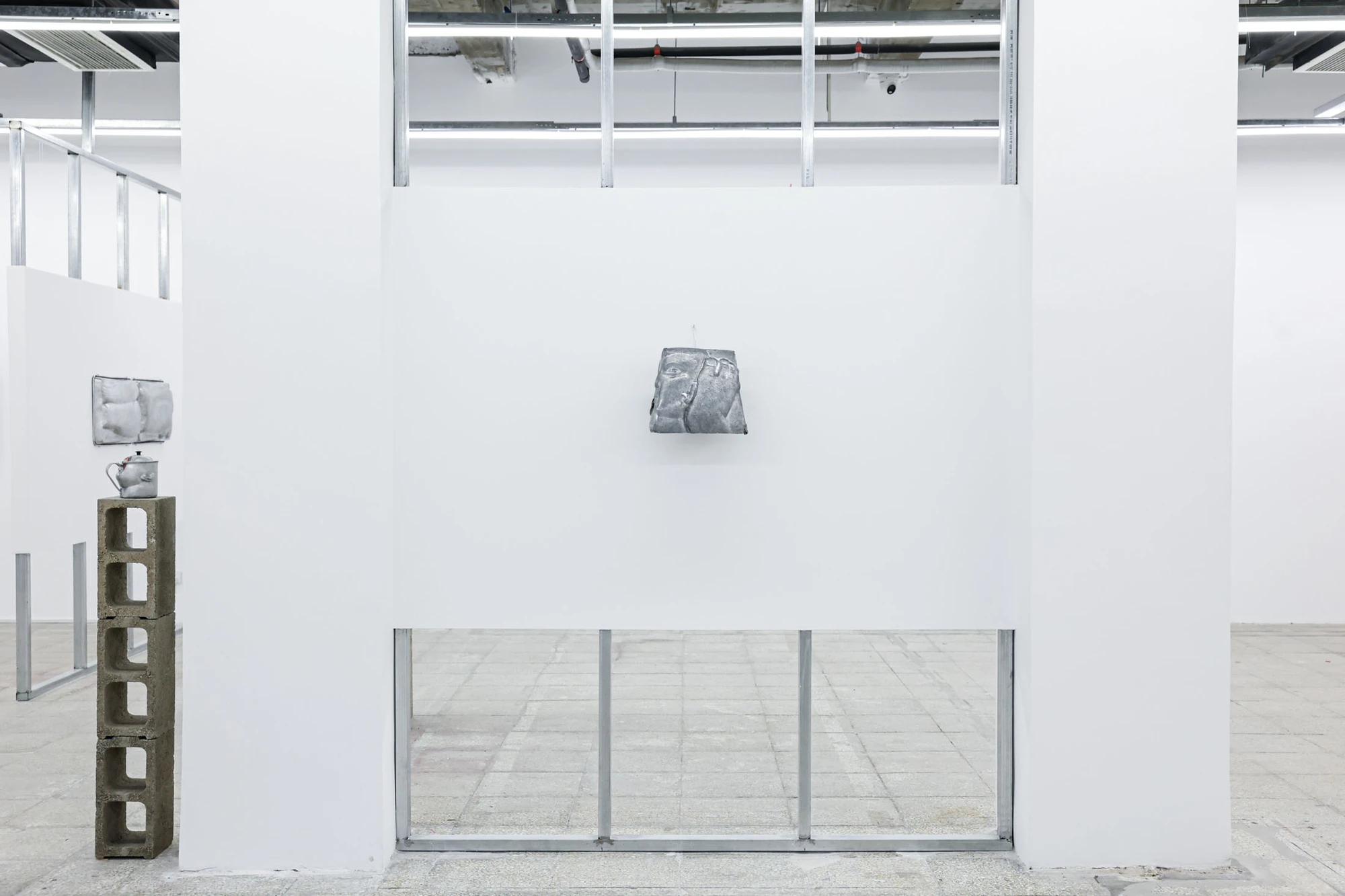 A User Guide by Tian Jianxin, photographed at Capsule — six hammered fragments, masks, a gourd-shaped head, a soup pot, scatter across a tall white wall like a constellation.