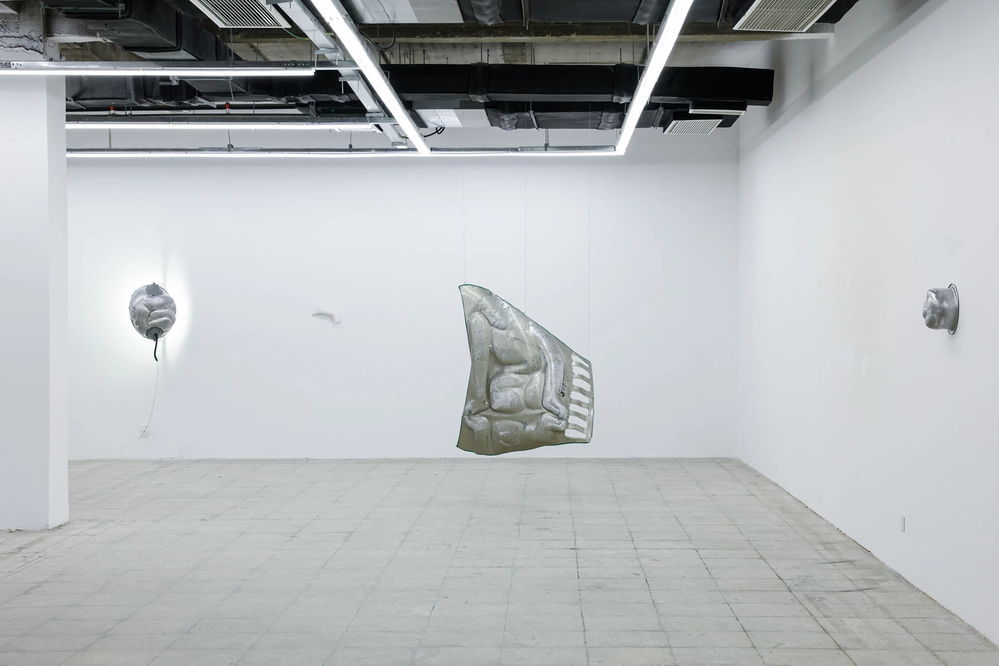 A User Guide by Tian Jianxin, photographed at Capsule — a wide-angle view of the gallery's exposed-duct ceiling, with vessels balanced on cinder blocks and small reliefs scattered across white partitions.