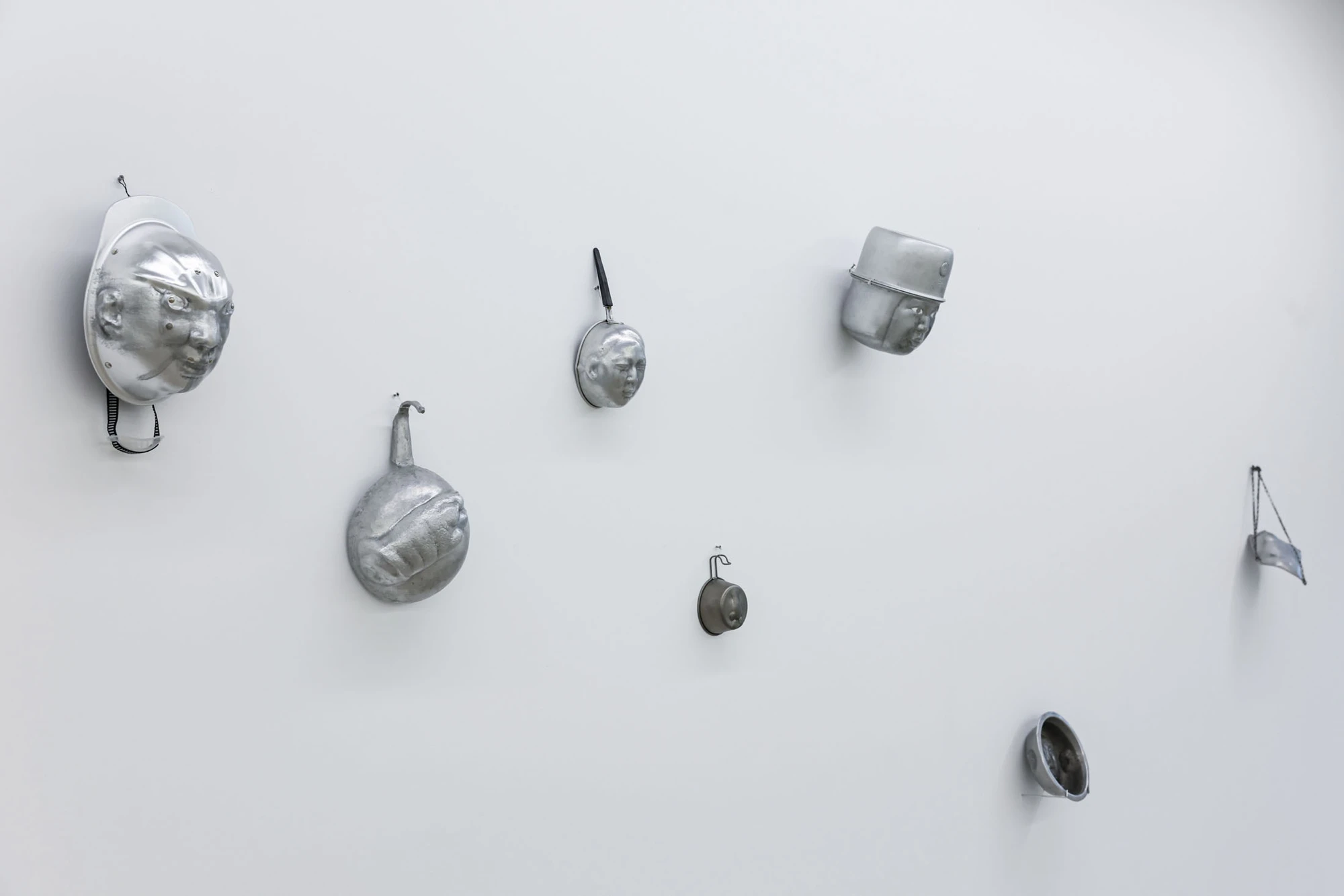 A User Guide by Tian Jianxin, photographed at Capsule — a cluster of fragments on a column wall, a kettle on a cinder-block plinth, and a dome-shaped lamp hanging from a long cord.