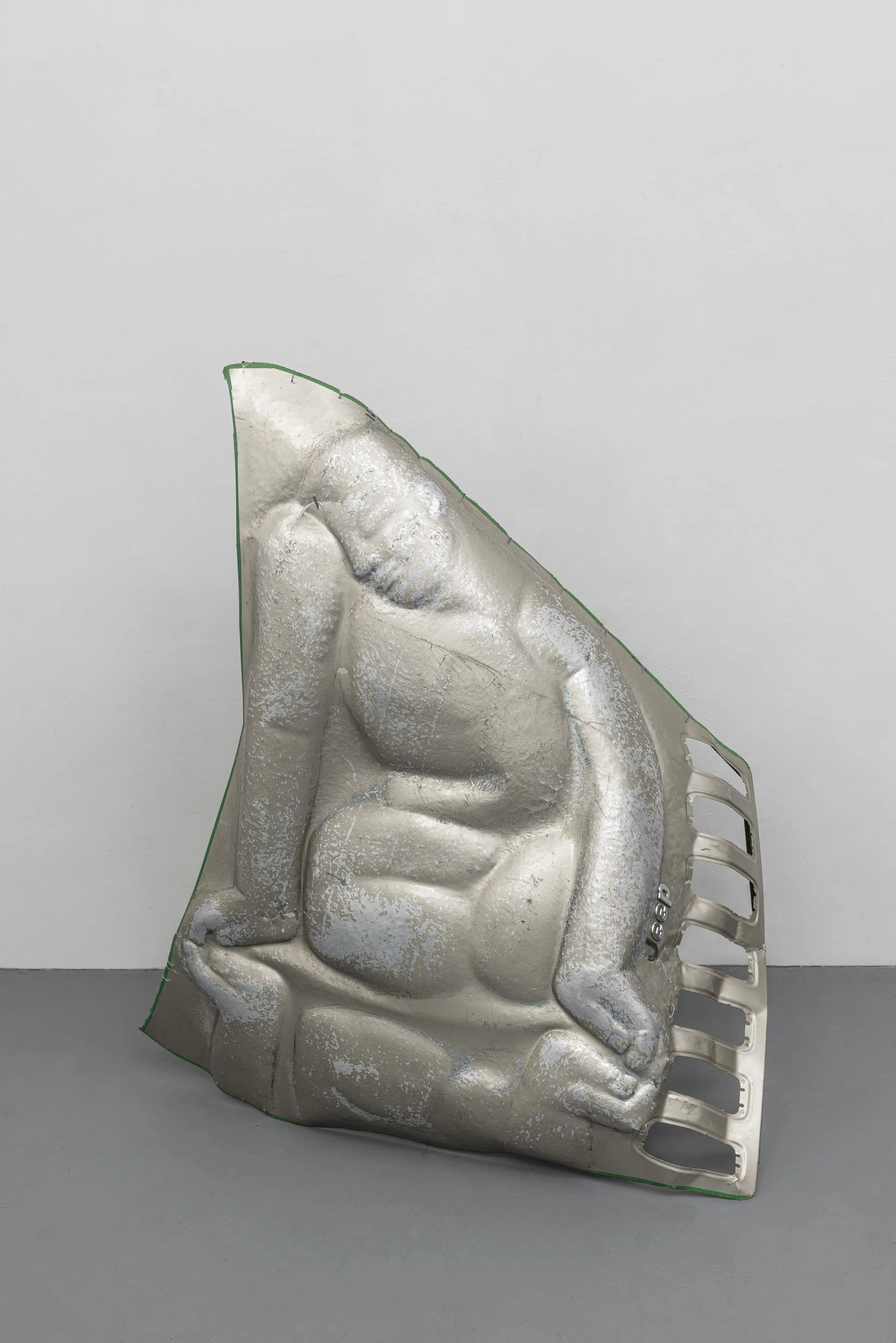 A User Guide by Tian Jianxin, photographed at Capsule — a green car hood floats mid-room beside a row of hammered fragments and a wall-mounted searchlight pressed flat into a relief.