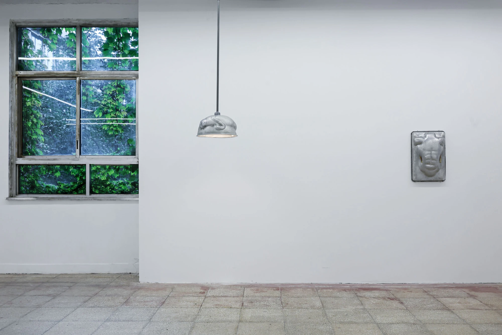 A User Guide by Tian Jianxin, photographed at Capsule — a vine-framed window flanked by hammered ladles and a small wall-mounted aluminium scoop, gallery floor in raw granite tile.