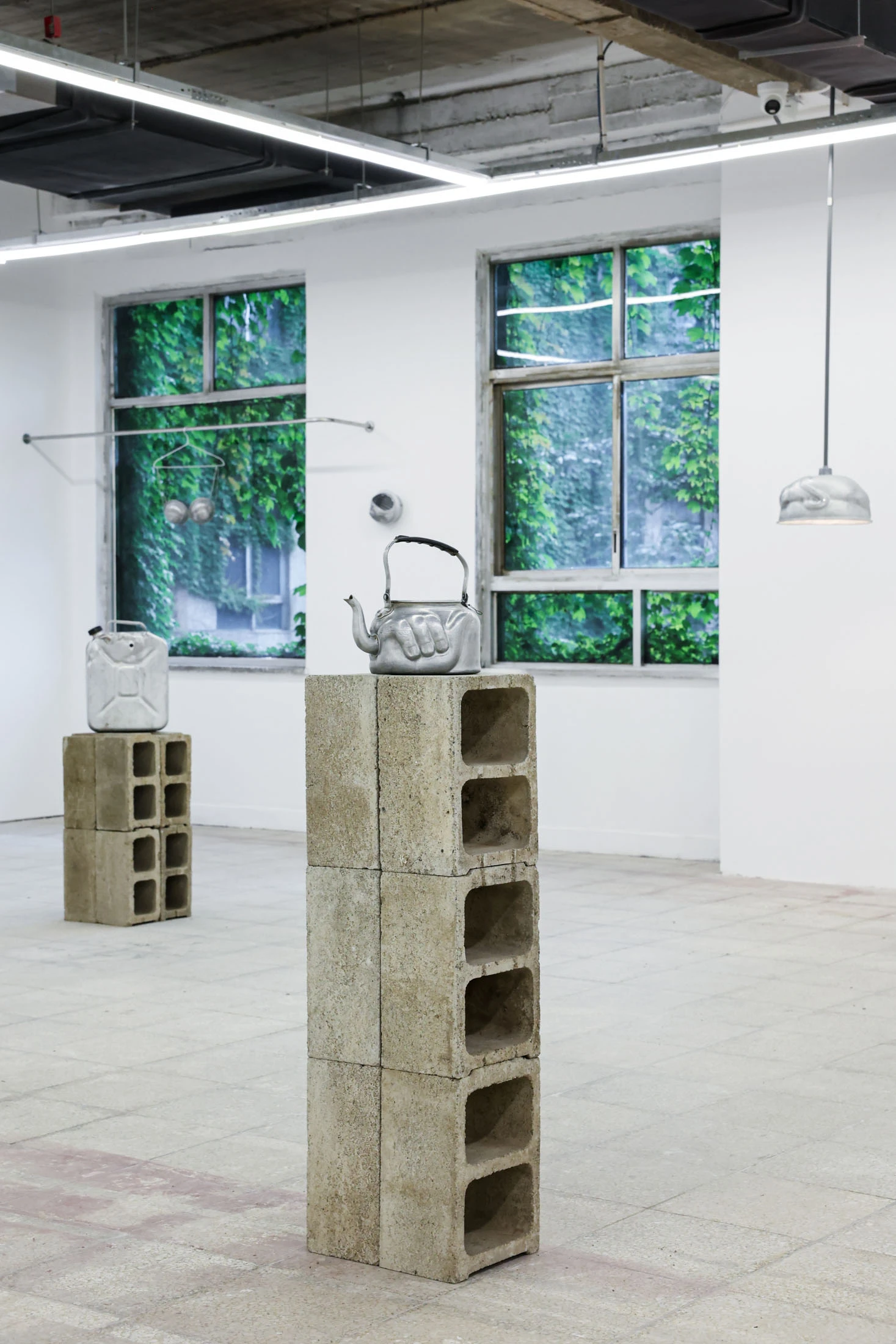 A User Guide by Tian Jianxin, photographed at Capsule — a partition wall holds a single small face cast in aluminium, framed by a cinder-block plinth and steel studs.