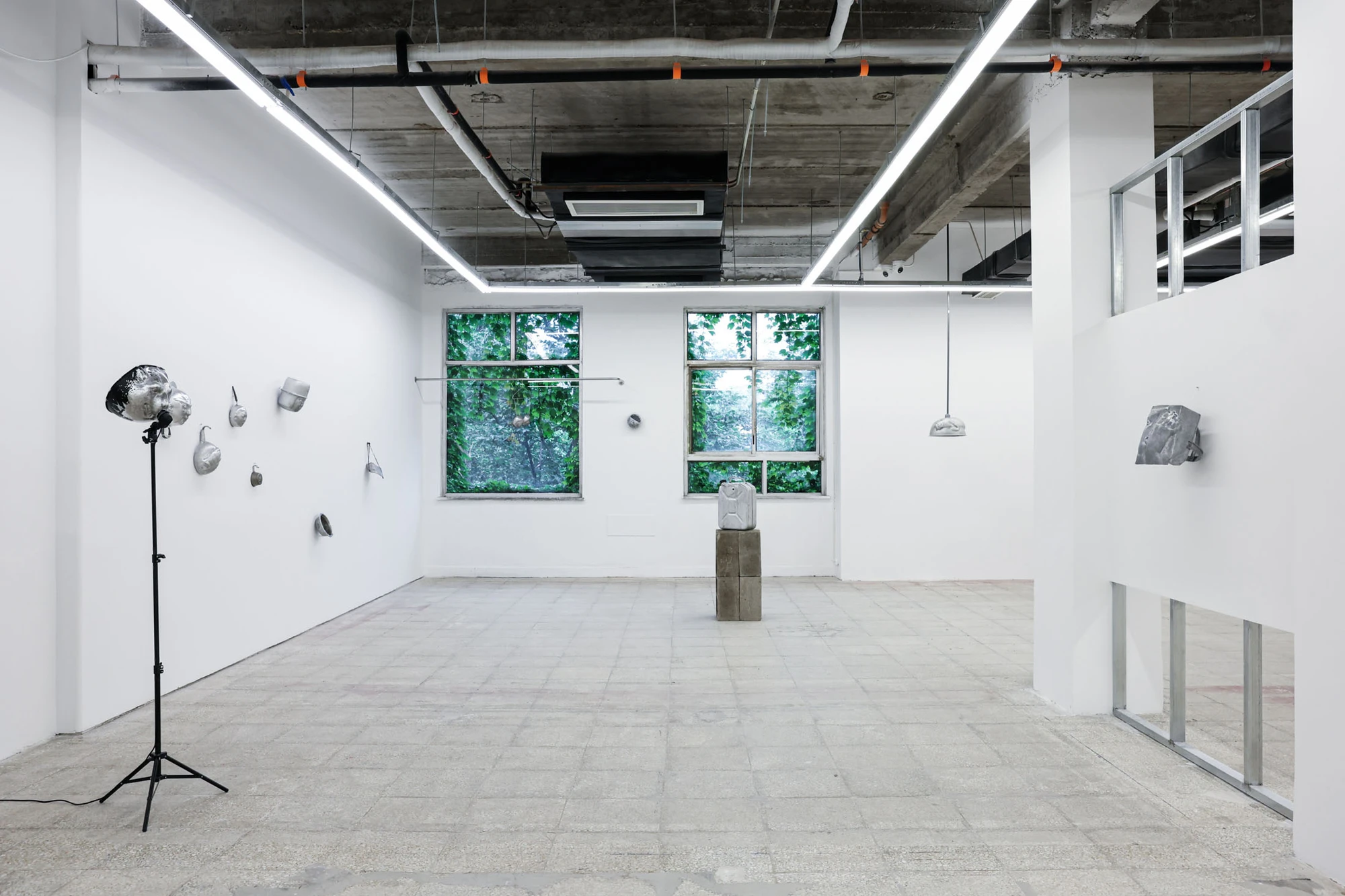 A User Guide by Tian Jianxin, photographed at Capsule — a tinted plastic car hood hangs in the center of the room, paired with a small wall-mounted aluminium mask on each flanking wall.
