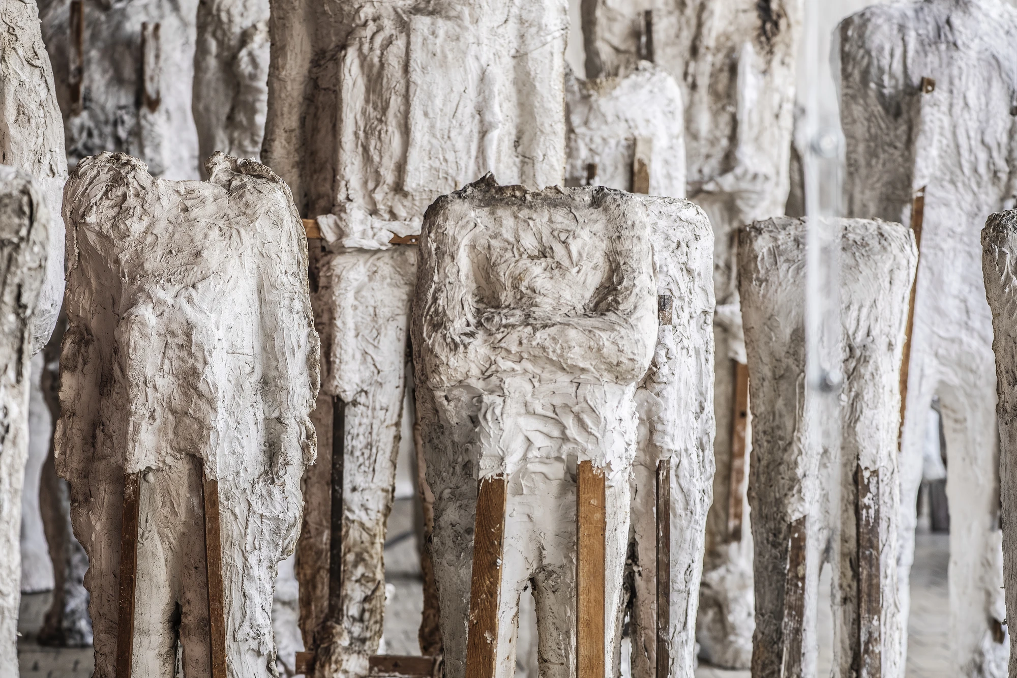 Magdalena Abakanowicz / Wanda Czełkowska by Abakanowicz Foundation, photographed by Norbert Piwowarczyk — Czełkowska's multiplied plaster heads in dense ranks on raw timber crates and stools.