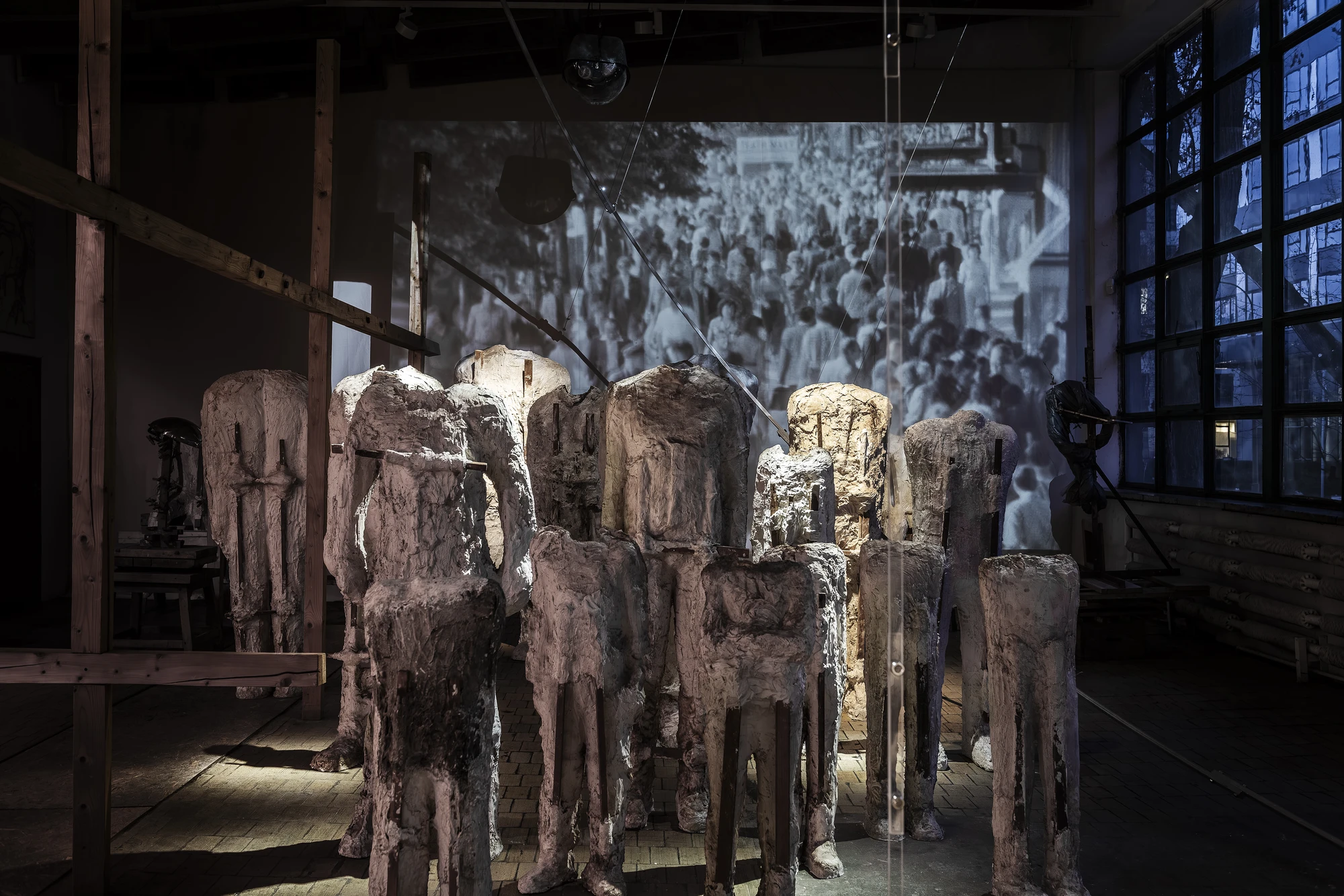 Magdalena Abakanowicz / Wanda Czełkowska by Abakanowicz Foundation, photographed by Norbert Piwowarczyk — a green-tinted plaster head on a tall white plinth between rows of white heads on timber stools.
