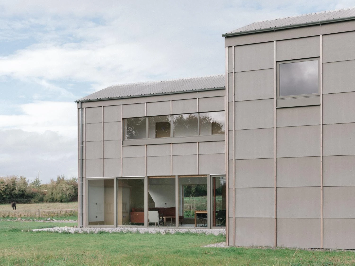 Suburban Family House by O.B. Architect, photographed by Shantanu Starick — clerestory glazing across the rear elevation reveals the living room, with cement-board cladding articulated by vertical timber battens.