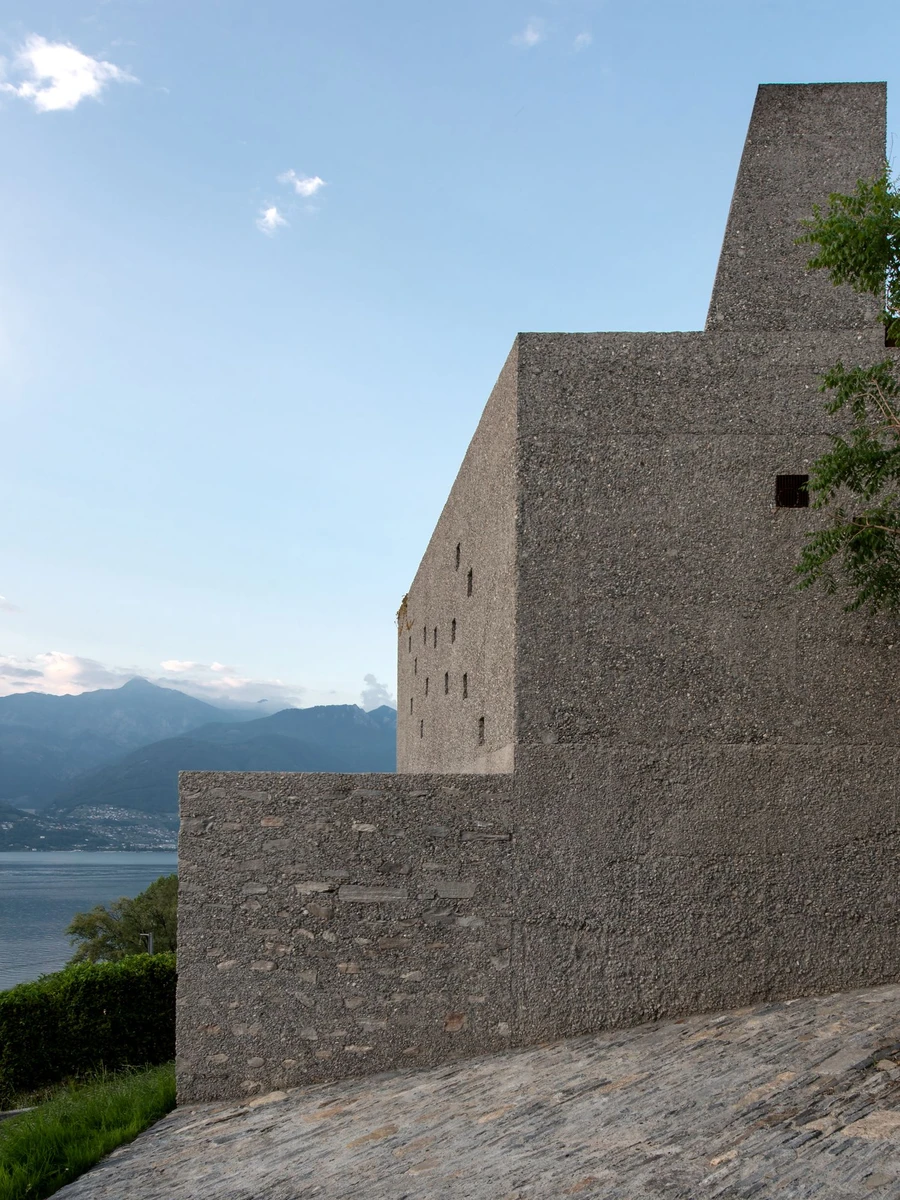New House in San Nazzaro by Wespi de Meuron Romeo, photographed by Giacomo Albo — the corten-clad chimney rising above the aggregate-exposed concrete mass.