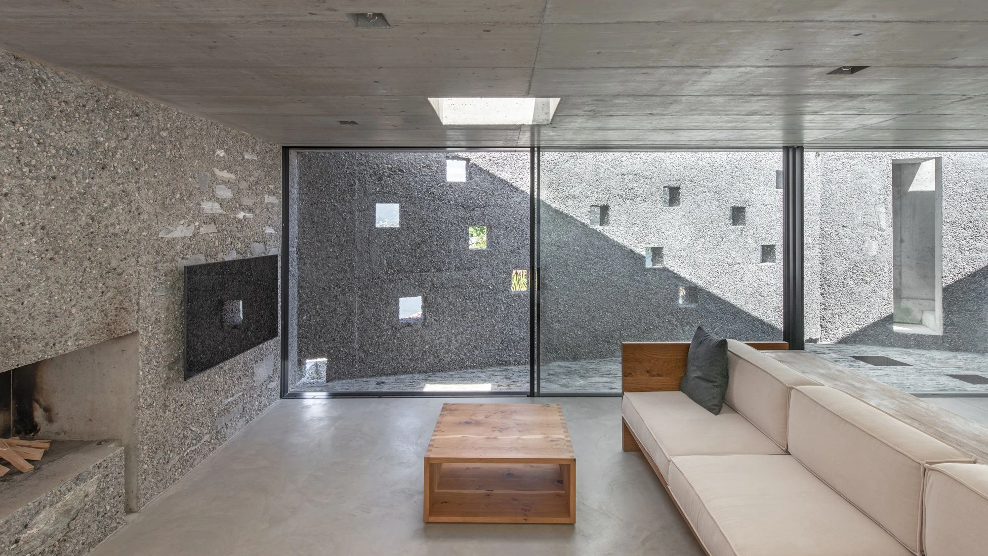 New House in San Nazzaro by Wespi de Meuron Romeo, photographed by Giacomo Albo — the living room with oak coffee table and full-height glazing onto the courtyard.