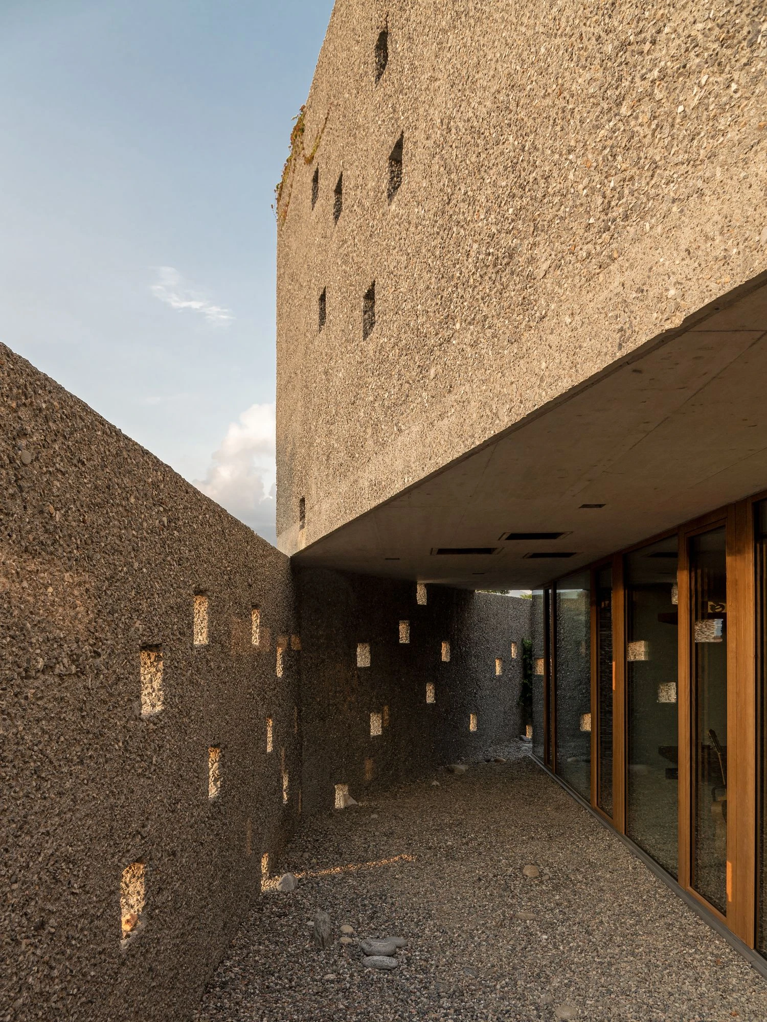 New House in San Nazzaro by Wespi de Meuron Romeo, photographed by Giacomo Albo — late afternoon light raking across the inner courtyard wall and its punched openings.