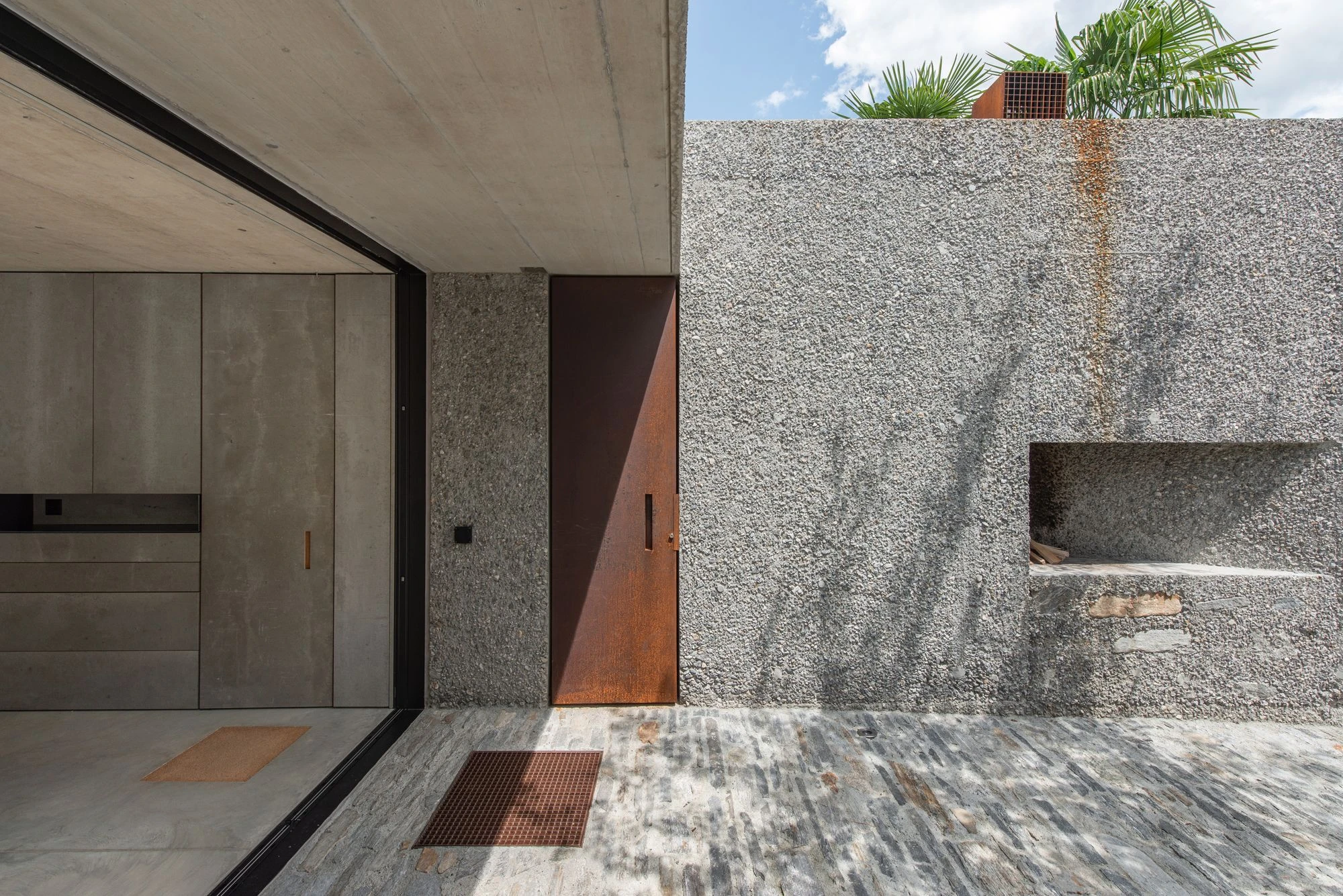 New House in San Nazzaro by Wespi de Meuron Romeo, photographed by Giacomo Albo — climbing plants beginning to take hold on the aggregate concrete wall.