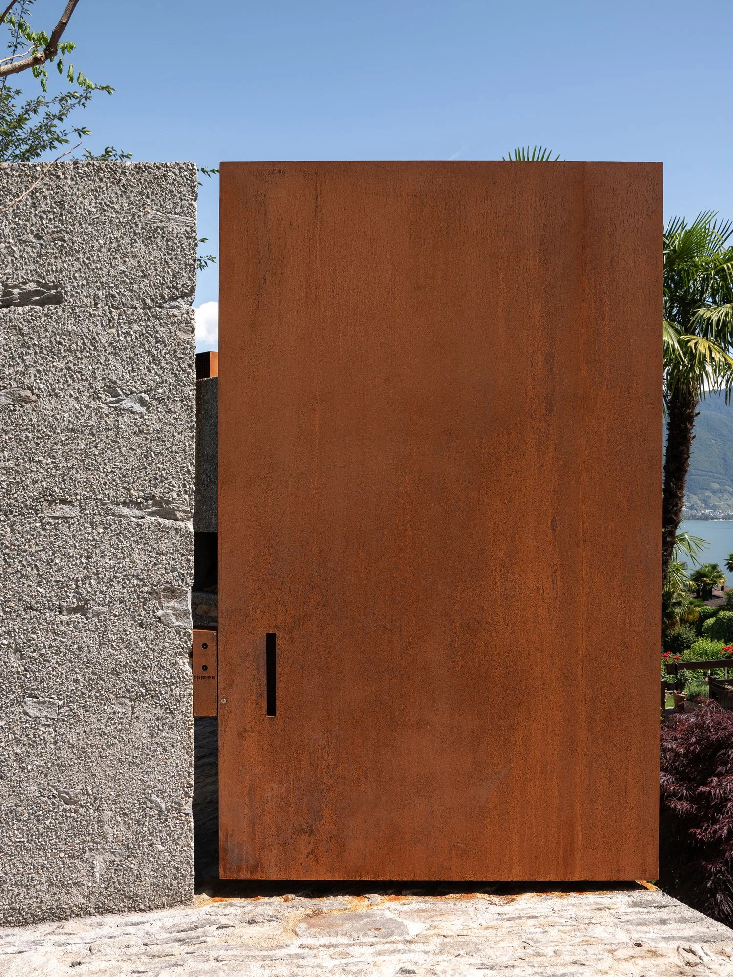 New House in San Nazzaro by Wespi de Meuron Romeo, photographed by Giacomo Albo — small square wall openings scattered across the rough washed-concrete face.