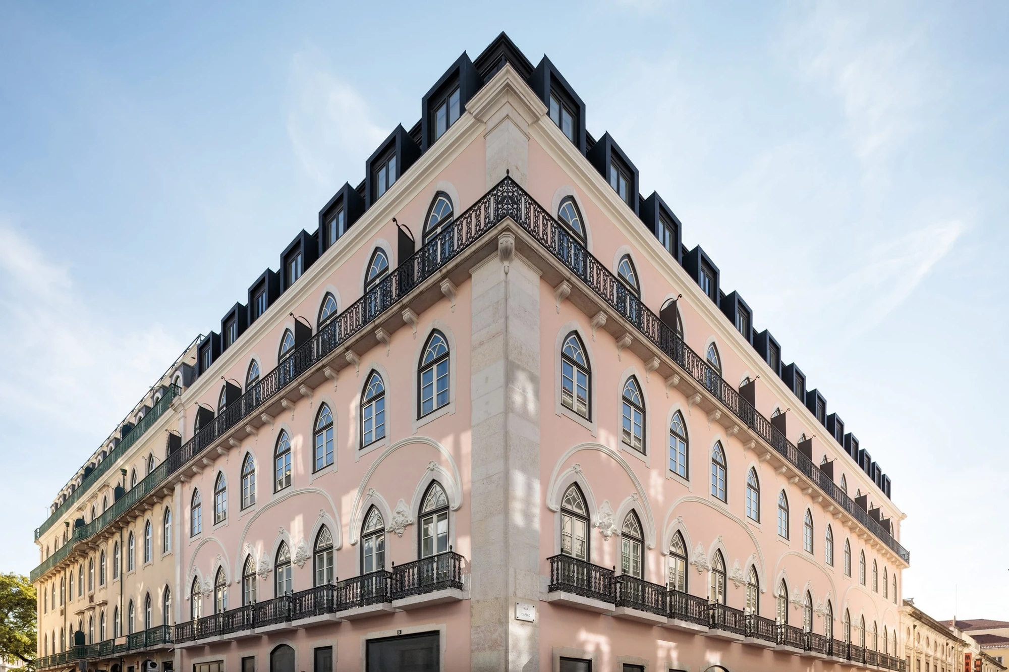 The Ivens by Lázaro Rosa-Violan, photographed by Francisco Nogueira — corner elevation at Rua Capelo with pink stucco, neo-Gothic windows and black mansard dormers.