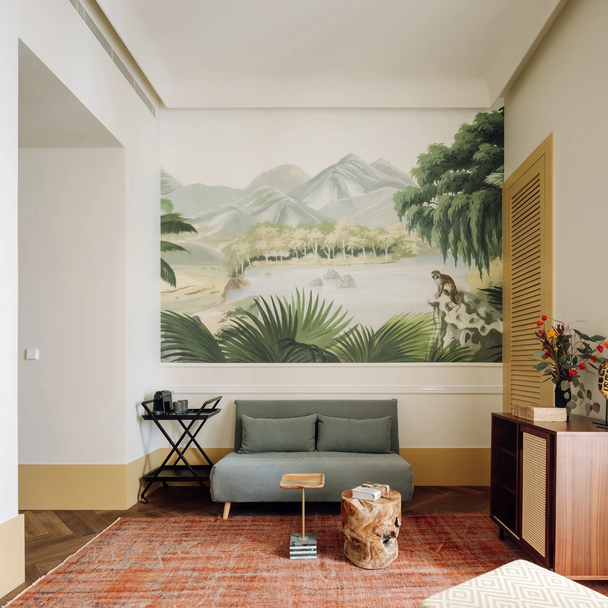 The Ivens by Lázaro Rosa-Violan, photographed by Francisco Nogueira — salon with panoramic jungle wallpaper, sage linen sofa and red Anatolian rug on herringbone parquet.