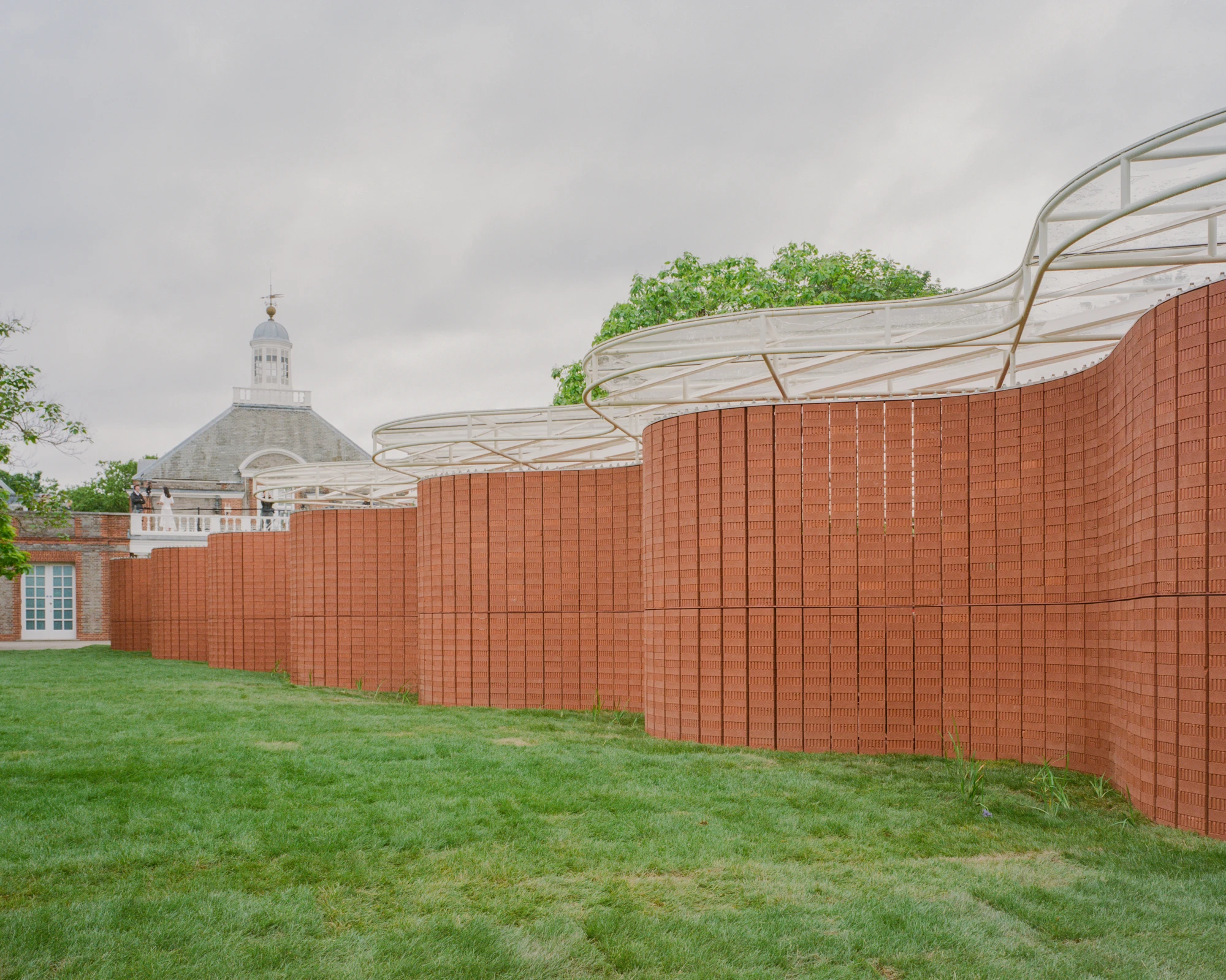 Serpentine Pavilion 2026 by LANZA atelier, photographed by Lorenzo Zandri — the long crinkle-crankle wall in elevation with the Serpentine South Gallery's cupola rising behind it.