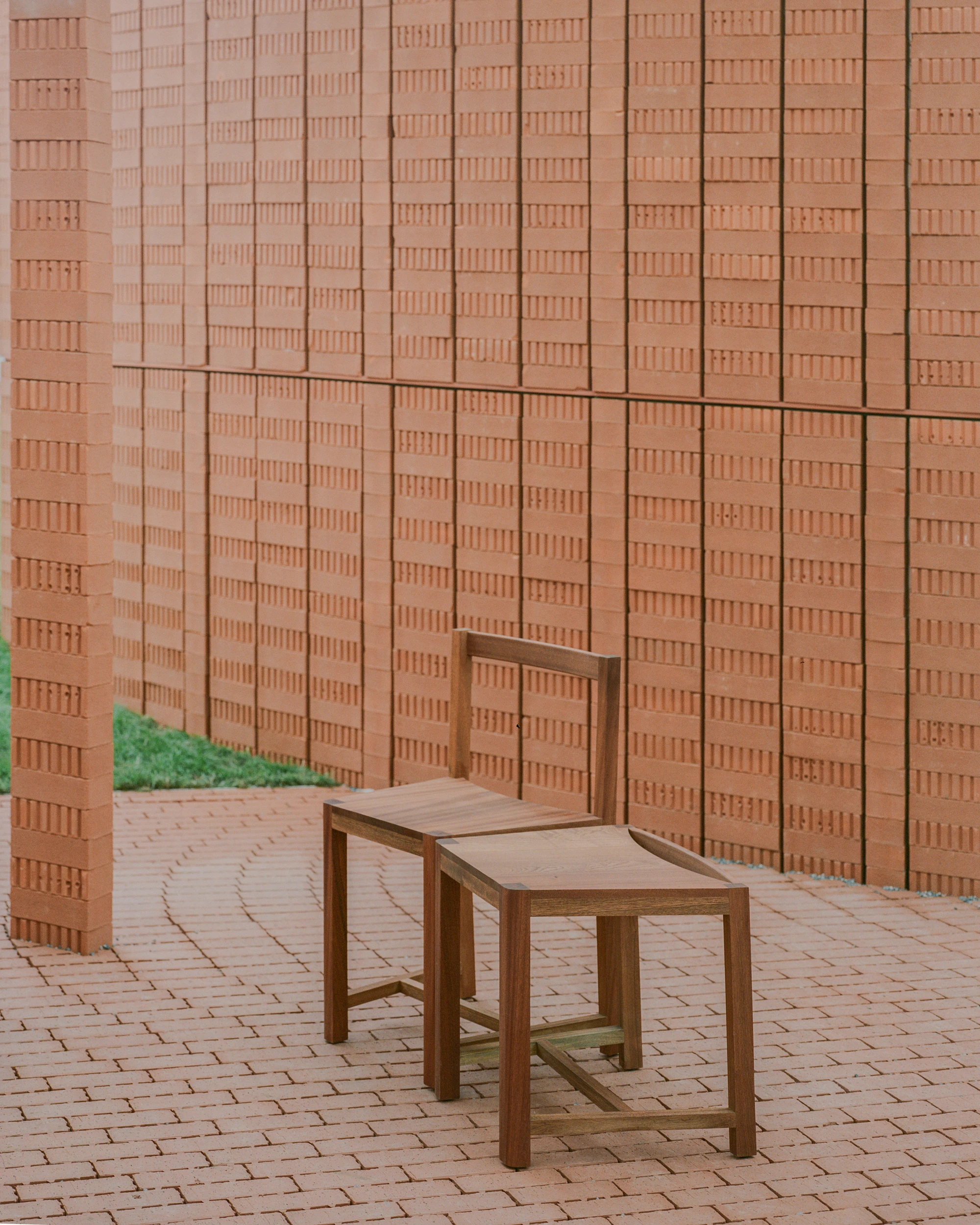 Serpentine Pavilion 2026 by LANZA atelier, photographed by Lorenzo Zandri — a single walnut chair on the radial brick paving against the perforated brick wall.