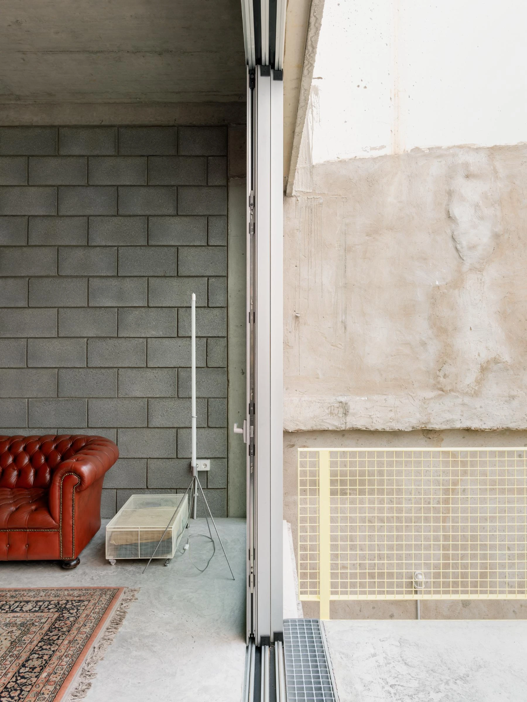 Casa Iriarte by SOCO Estudio, Simone Marcolin: threshold between interior and courtyard with picon block, aluminium track, yellow tile pool edge and the patinated render outside.
