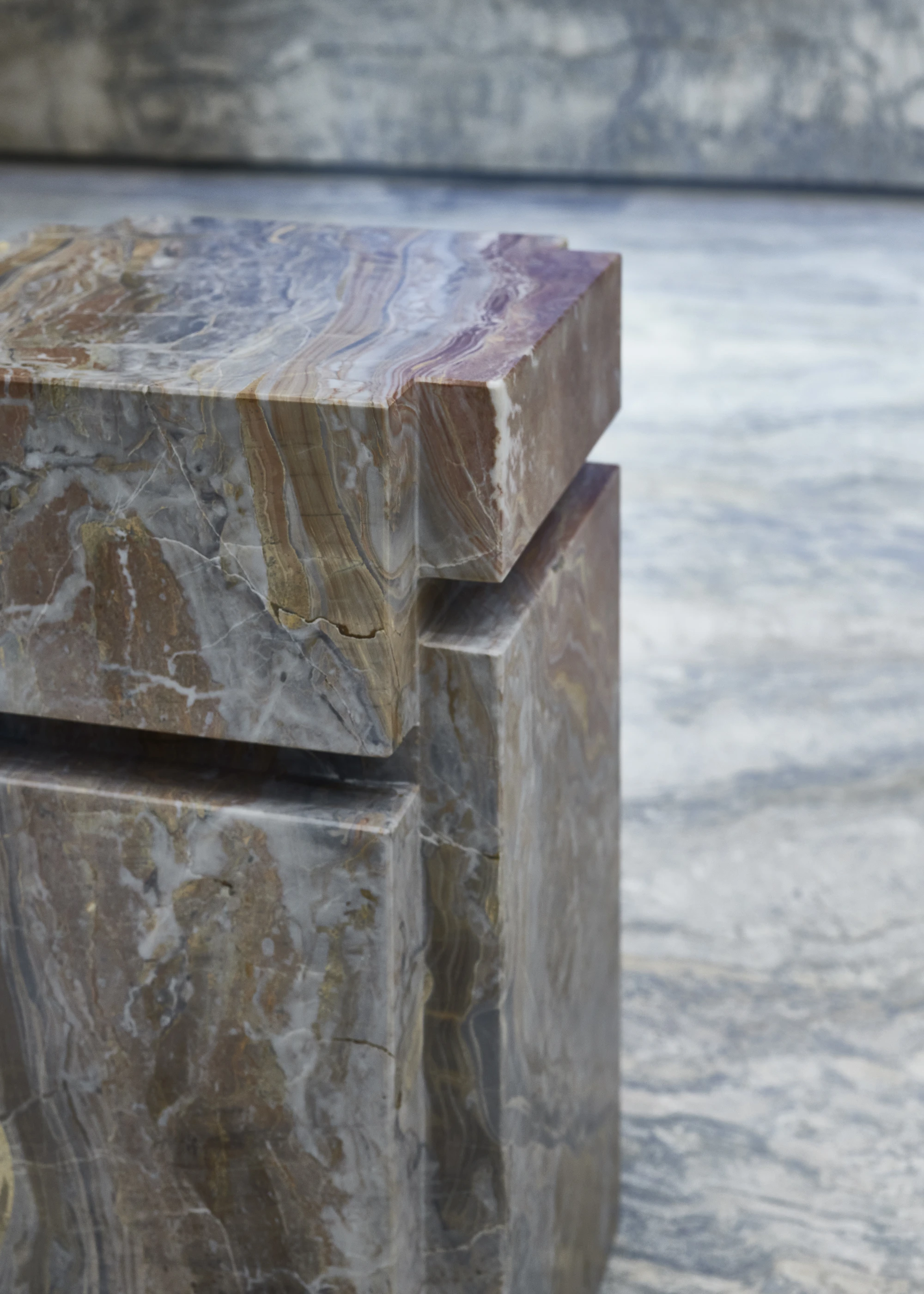 Jil Sander Flagship Store Ginza by Casper Mueller Kneer Architects, photographed by Paul Riddle — close detail of a banded marble sculpture by Rachel Whiteread, ochre and purple veining catching light against silver-blue travertine.