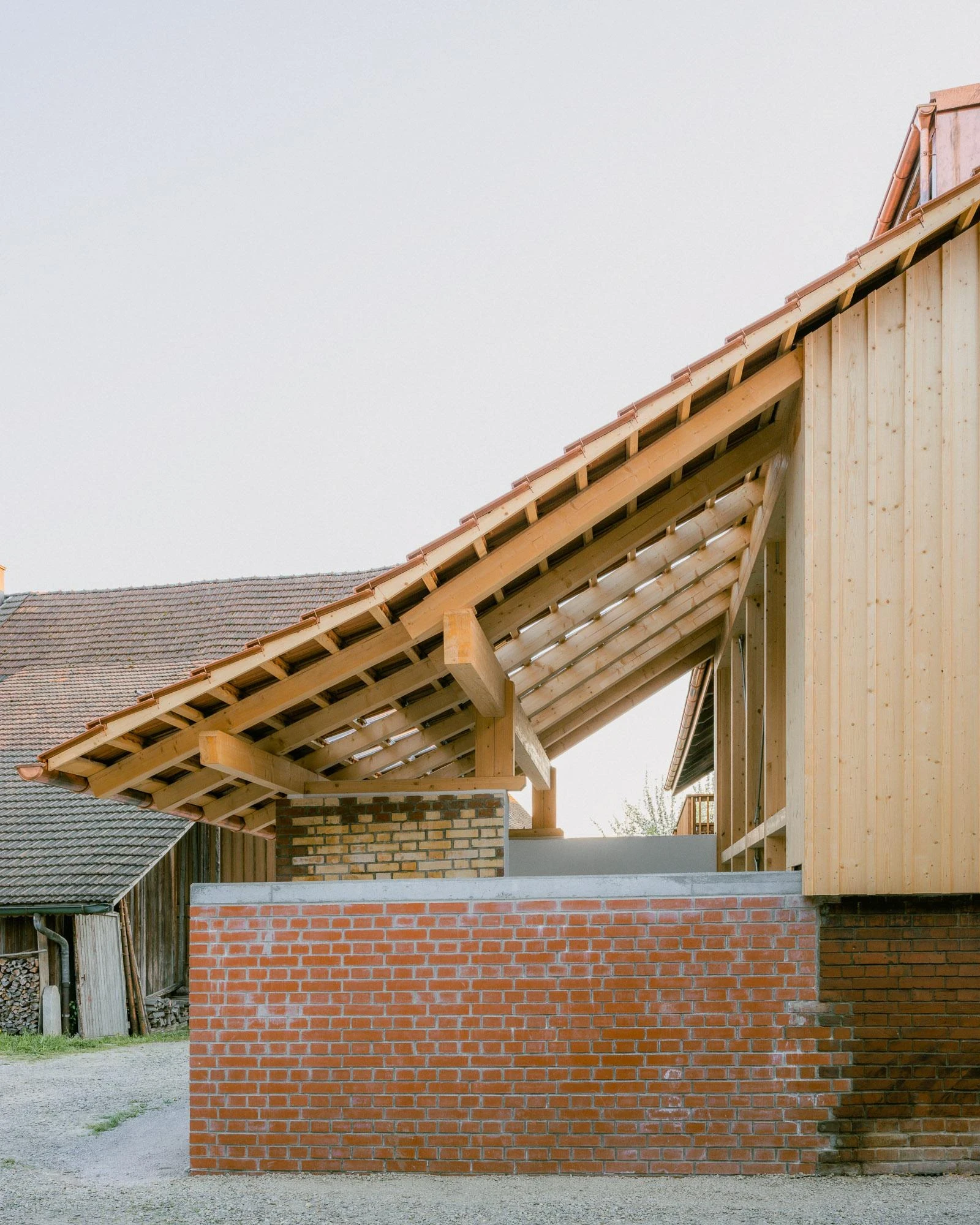 Barn Conversion in Hettlingen by Orso Dettling, photographed by Jeremiah Schwery — Eaves detail of the covered terrace, exposed rafters and tile underside cantilevered over a fresh brick parapet