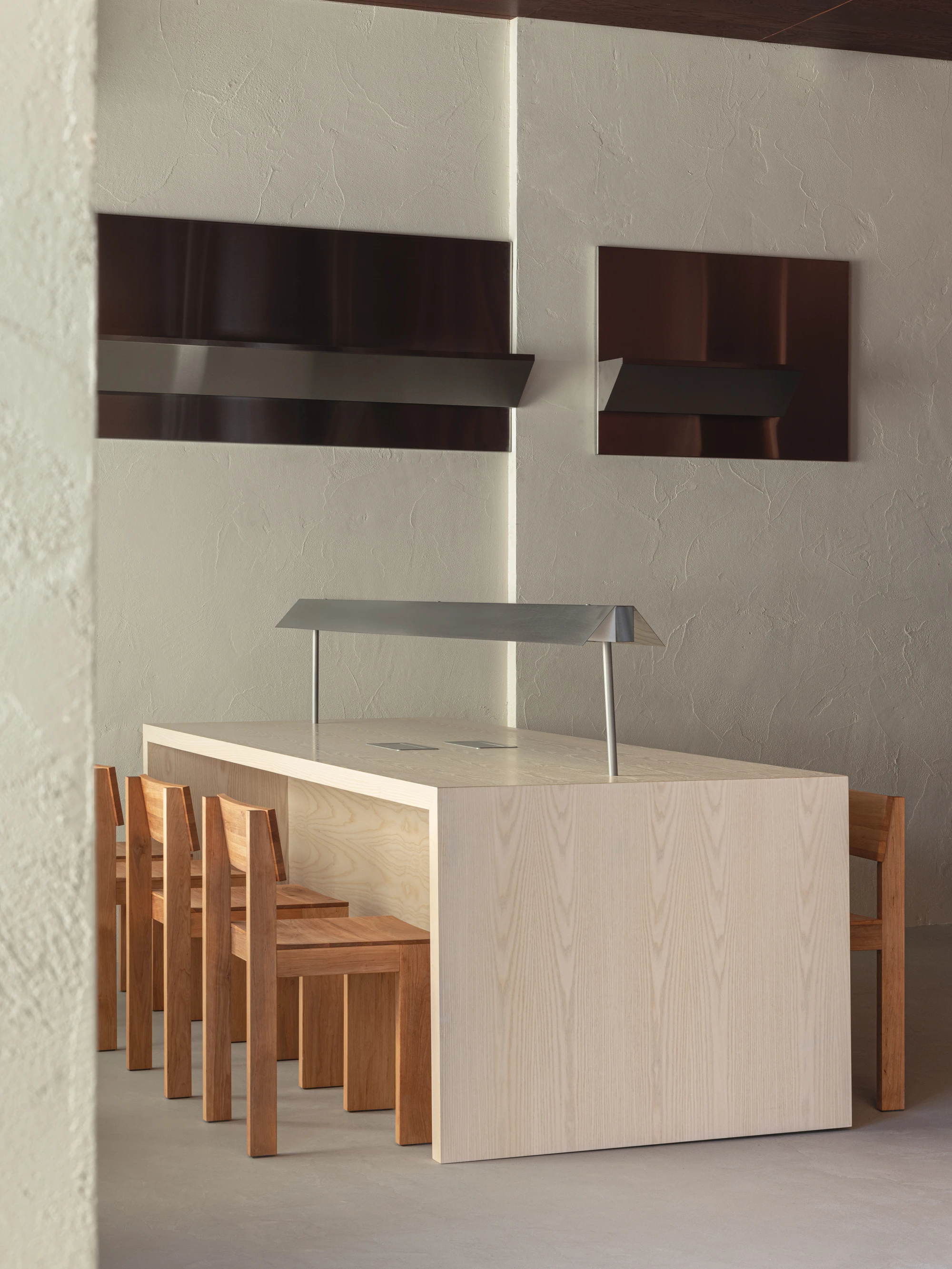 Biblioteka Coffee by Kidz, photographed by Alexander Plyaskin — the pale ash communal table runs the length of the silence room, flanked by stick-frame oak chairs and two recessed polished steel lightboxes mounted on the plaster wall.