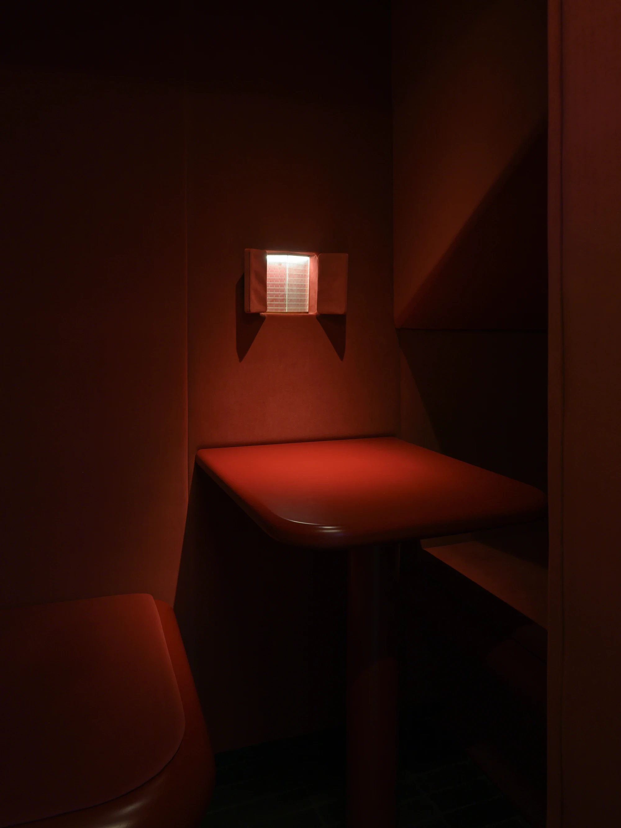 OKN Restaurant by SAGA, photographed by Daniel Annenkov — The private crimson booth: walls, ceiling, and curved table edge are all in the same deep red lacquer. A single small illuminated panel glows on the wall above the table.