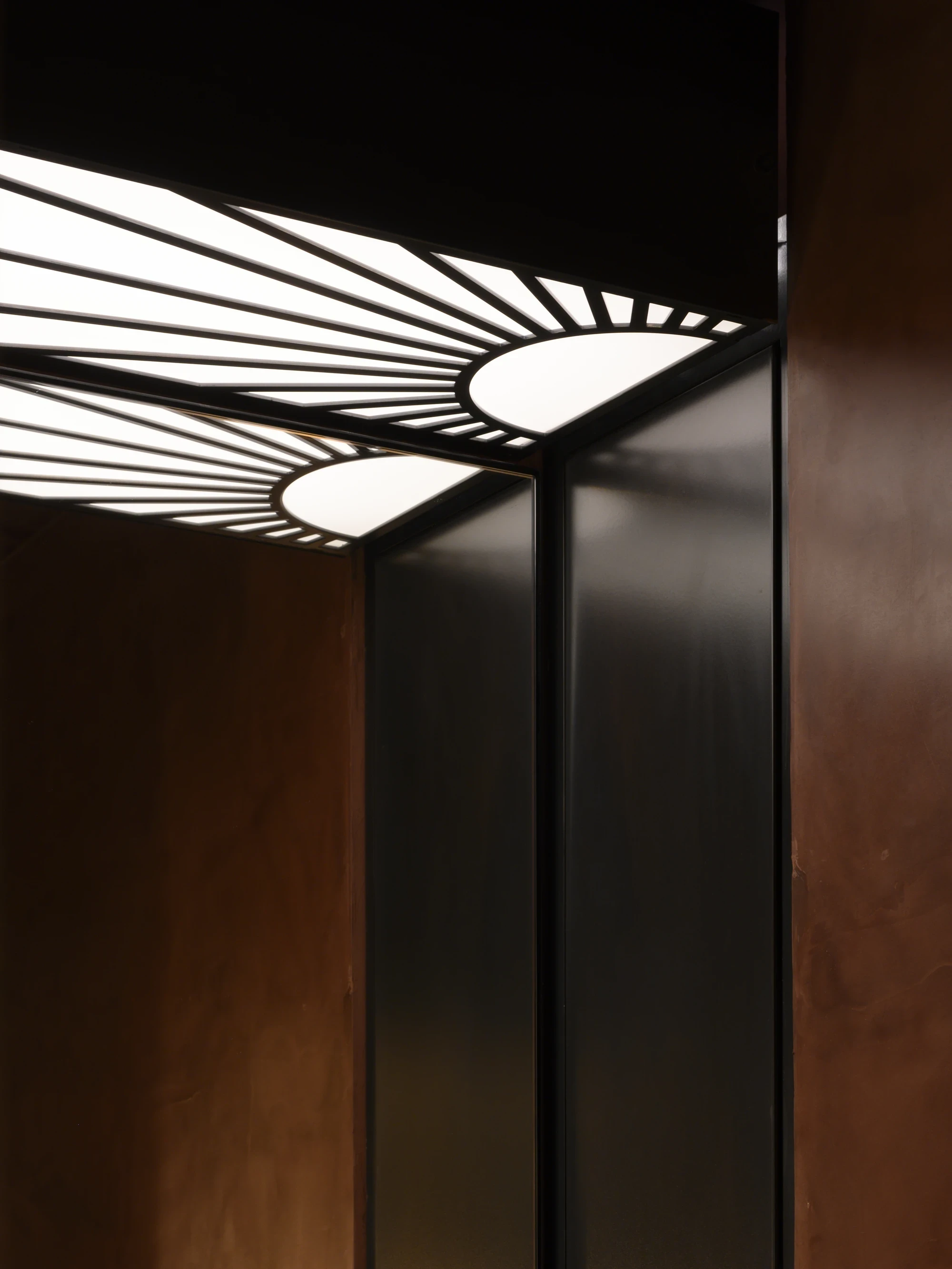 OKN Restaurant by SAGA, photographed by Daniel Annenkov — Detail of the bathroom ceiling: a stained-glass-scale backlit panel with black steel armature in a radiating spoke pattern, two white ovoid centres from which spokes extend to the rectangular frame