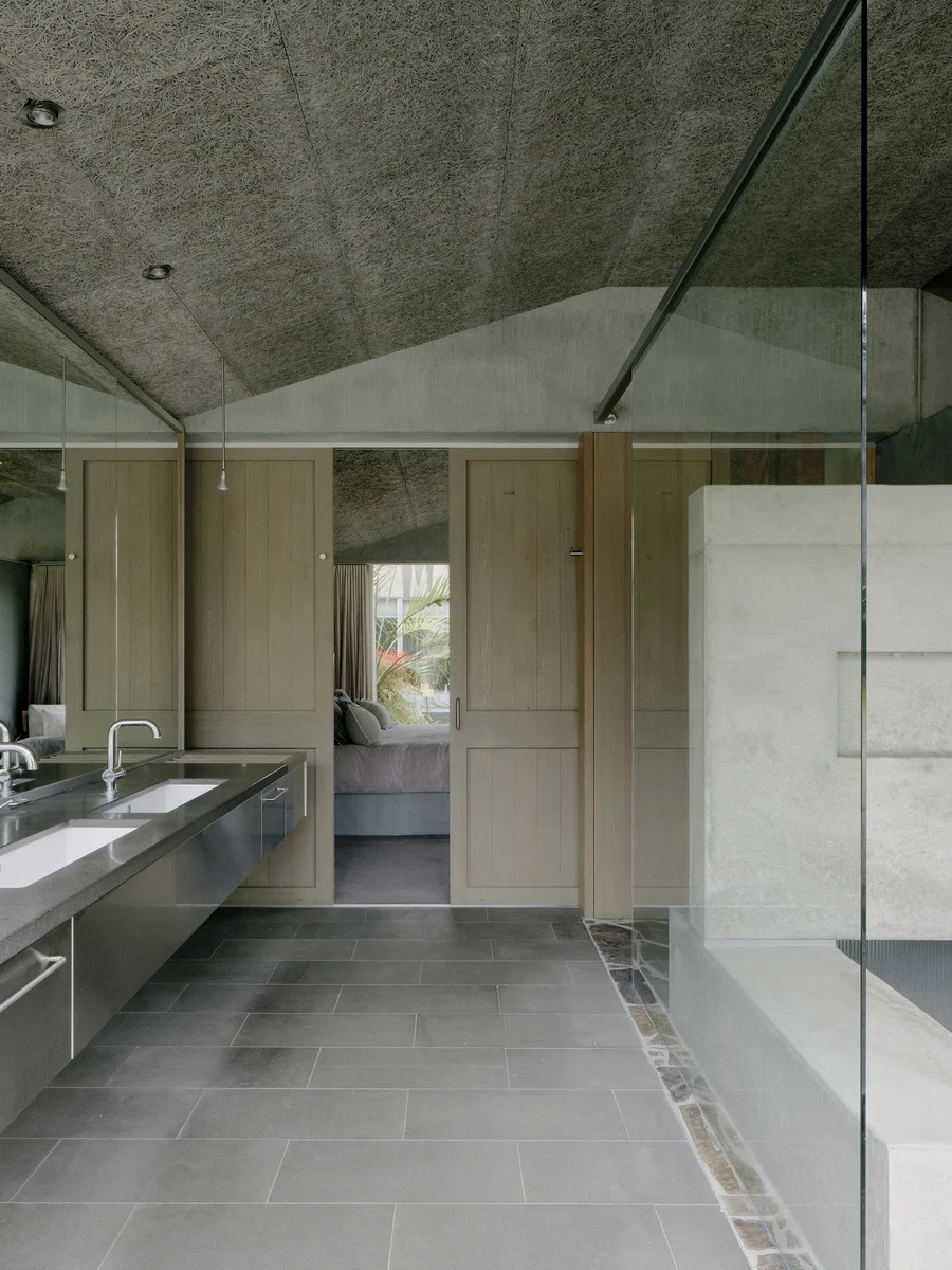 This is Lumeah by Pepper & Well, photographed by Tom Ross — The renewed ensuite seen from the vanity end: twin basins set into the original stainless steel bench beneath a wall-length mirror, the vaulted compressed-straw Stramit ceiling overhead and timbe