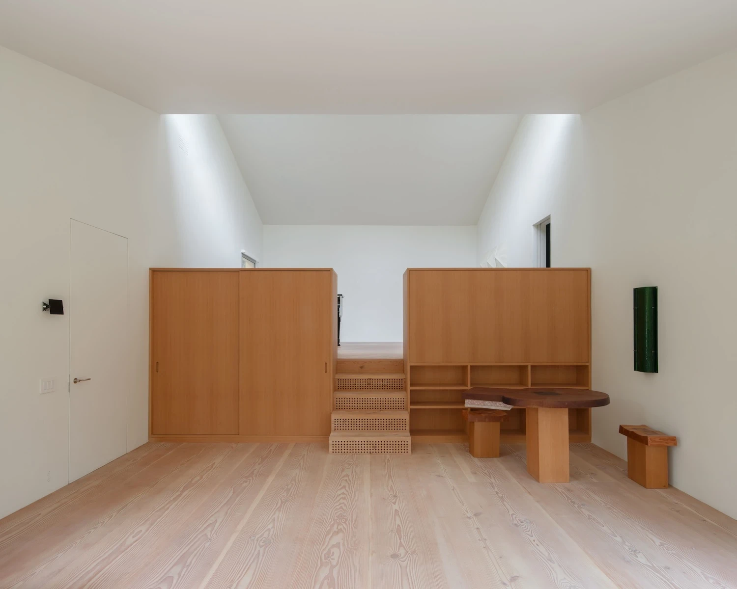 Studio & Guest House by Neil Logan, photographed by Mikael Olsson — upper level of the studio with twin clerestory light wells, fir cabinet volumes flanking the stair, cane-front risers, and a dark walnut live-edge table with fir stools below.