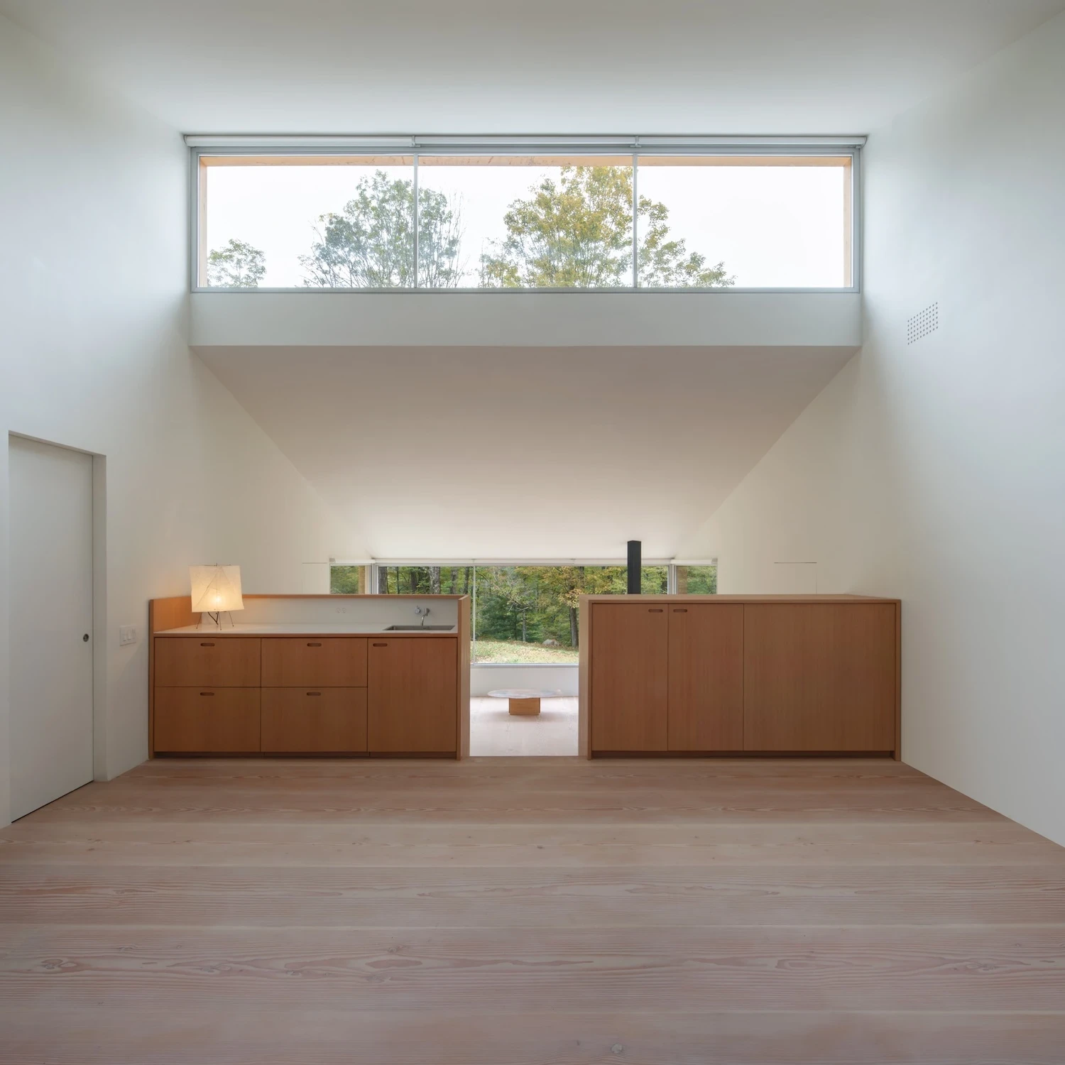 Studio & Guest House by Neil Logan, photographed by Mikael Olsson — the studio interior looking toward the fir millwork wall: honey-toned fir cabinets by Round Peg Millwork run wall-to-wall beneath a continuous clerestory band window.