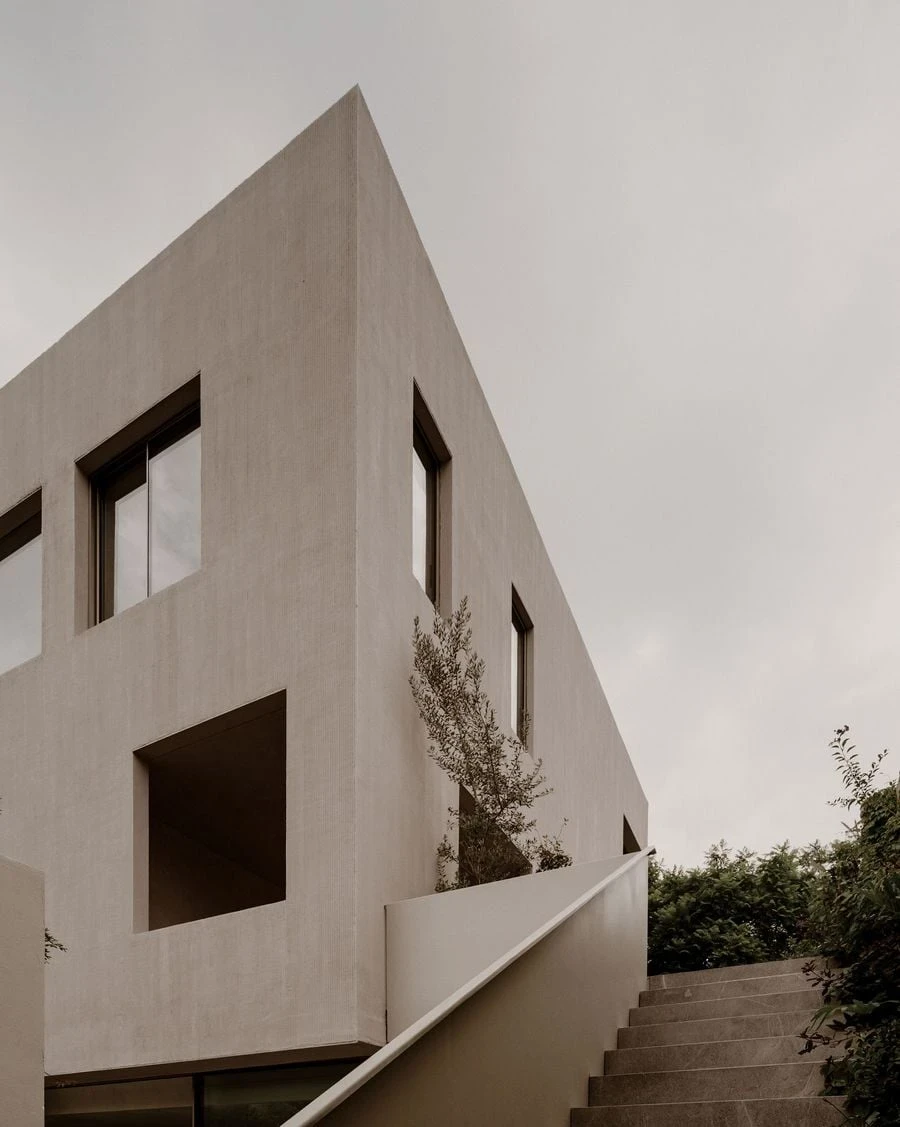 Barrancas by PPAA, photographed by Luis Garvan — mature vegetation frames the entry, the house visible only as glimpsed surface behind canopy and undergrowth.