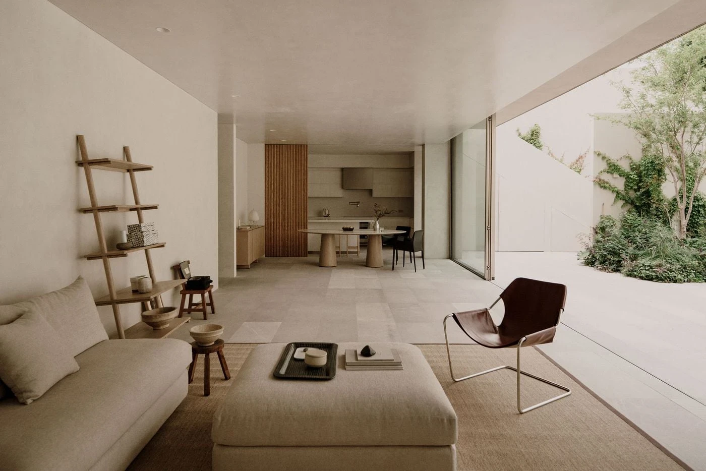 Barrancas by PPAA, photographed by Luis Garvan — floor-to-ceiling sliding glazing opens the rear terrace to the garden, honed stone tile running without interruption from interior to exterior.