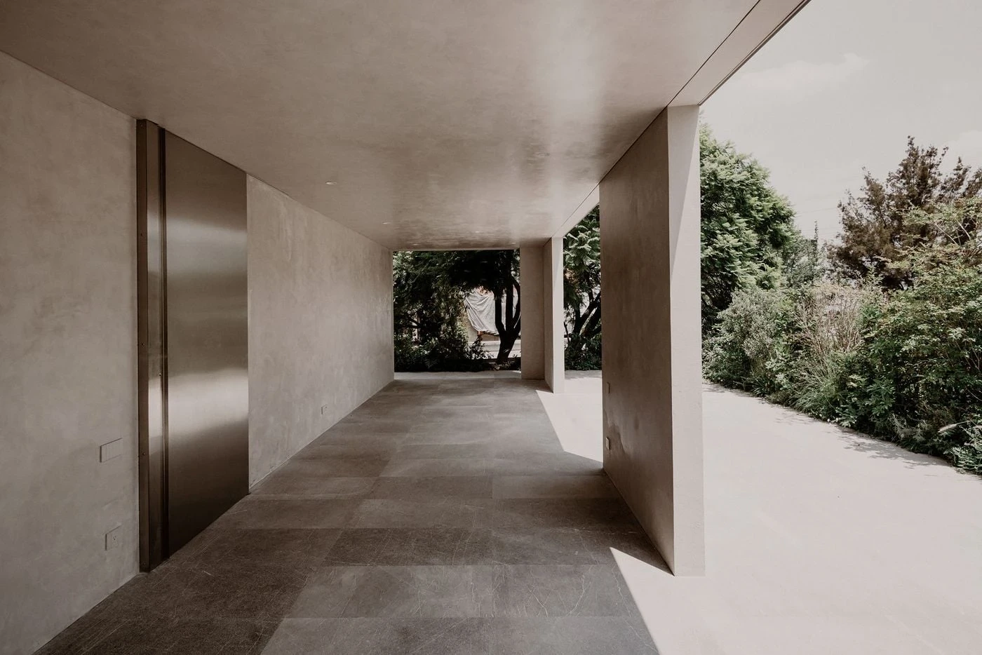Barrancas by PPAA, photographed by Luis Garvan — a sheltered terrace corner in warm plaster with a square window and potted plants, the loggia space carved by the displaced upper volume.
