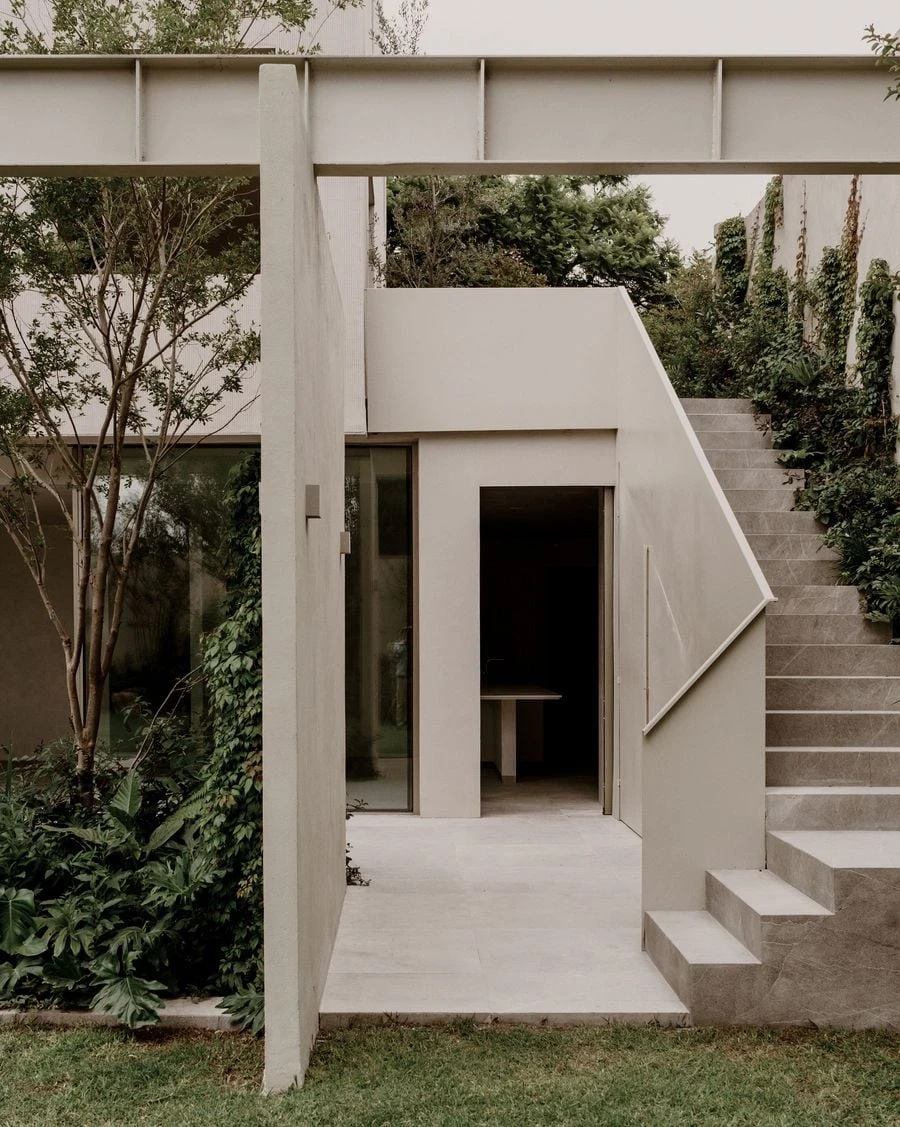Barrancas by PPAA, photographed by Luis Garvan — the pale plaster rear elevation seen from the garden, the cube's measured window rhythm set above a steel walkway spanning the recessed garden room.
