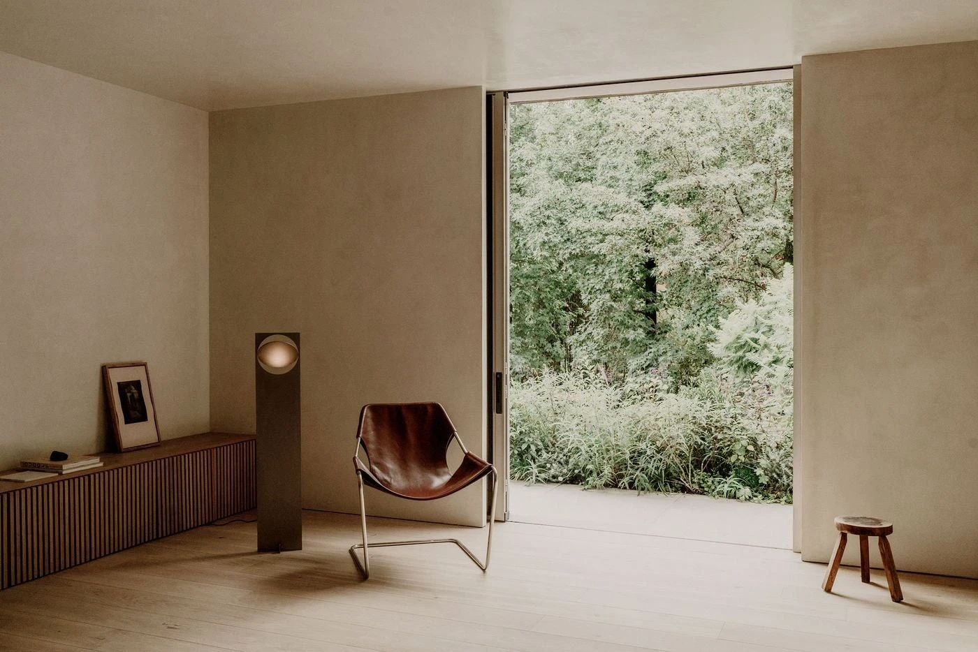 Barrancas by PPAA, photographed by Luis Garvan — the sofa faces sliding glazing fully open to the rear lawn, ivy-clad boundary walls beyond, the living room and garden occupying one continuous space.