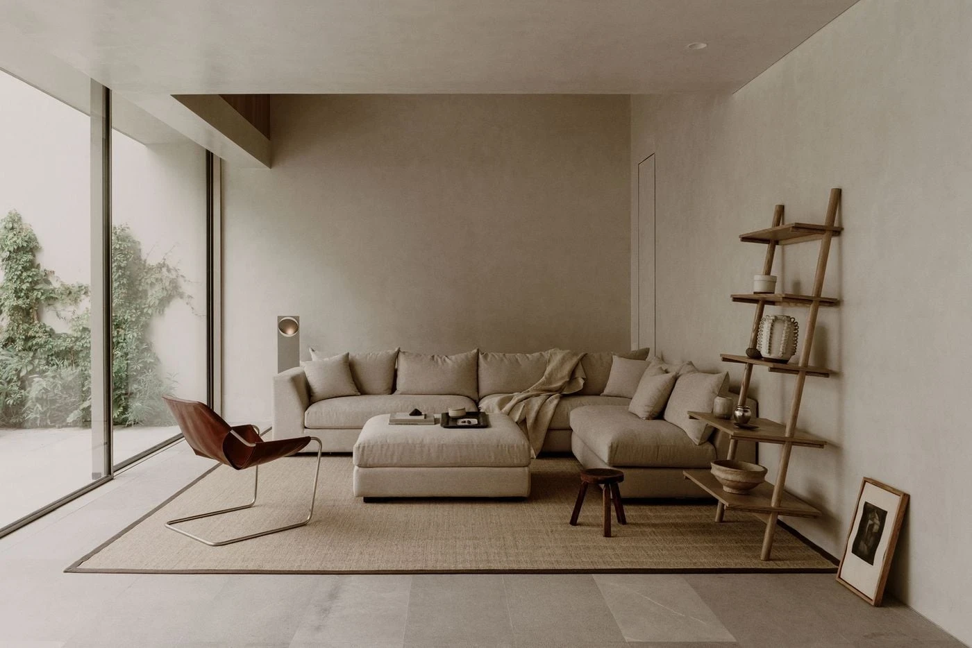 Barrancas by PPAA, photographed by Luis Garvan — the oval travertine dining table seen through the glazing from the courtyard, both sides of the threshold mirrored in material and tone.