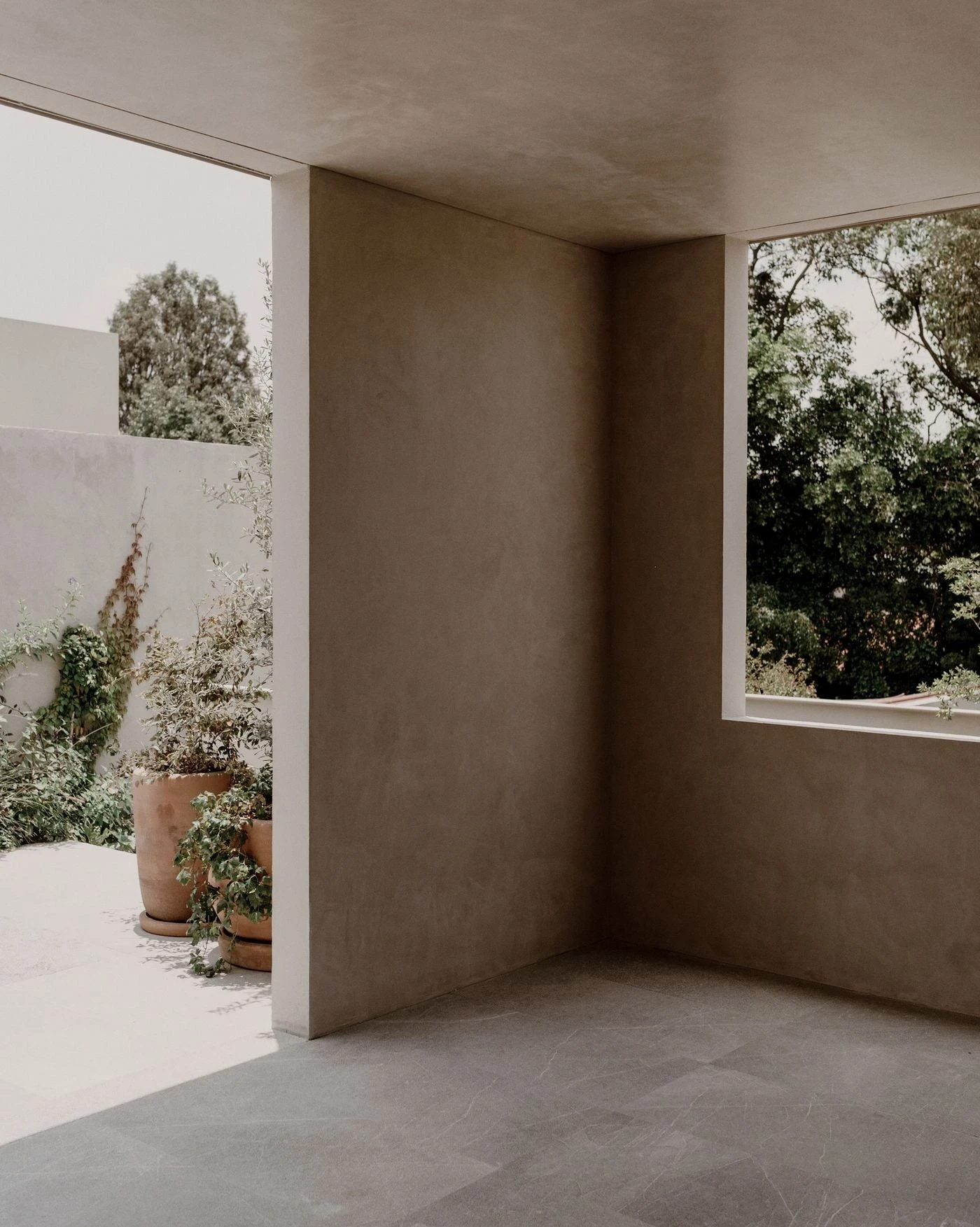 Barrancas by PPAA, photographed by Luis Garvan — striated plaster meets a recessed undercroft, a brushed metallic door set into the transition between the two volumes.