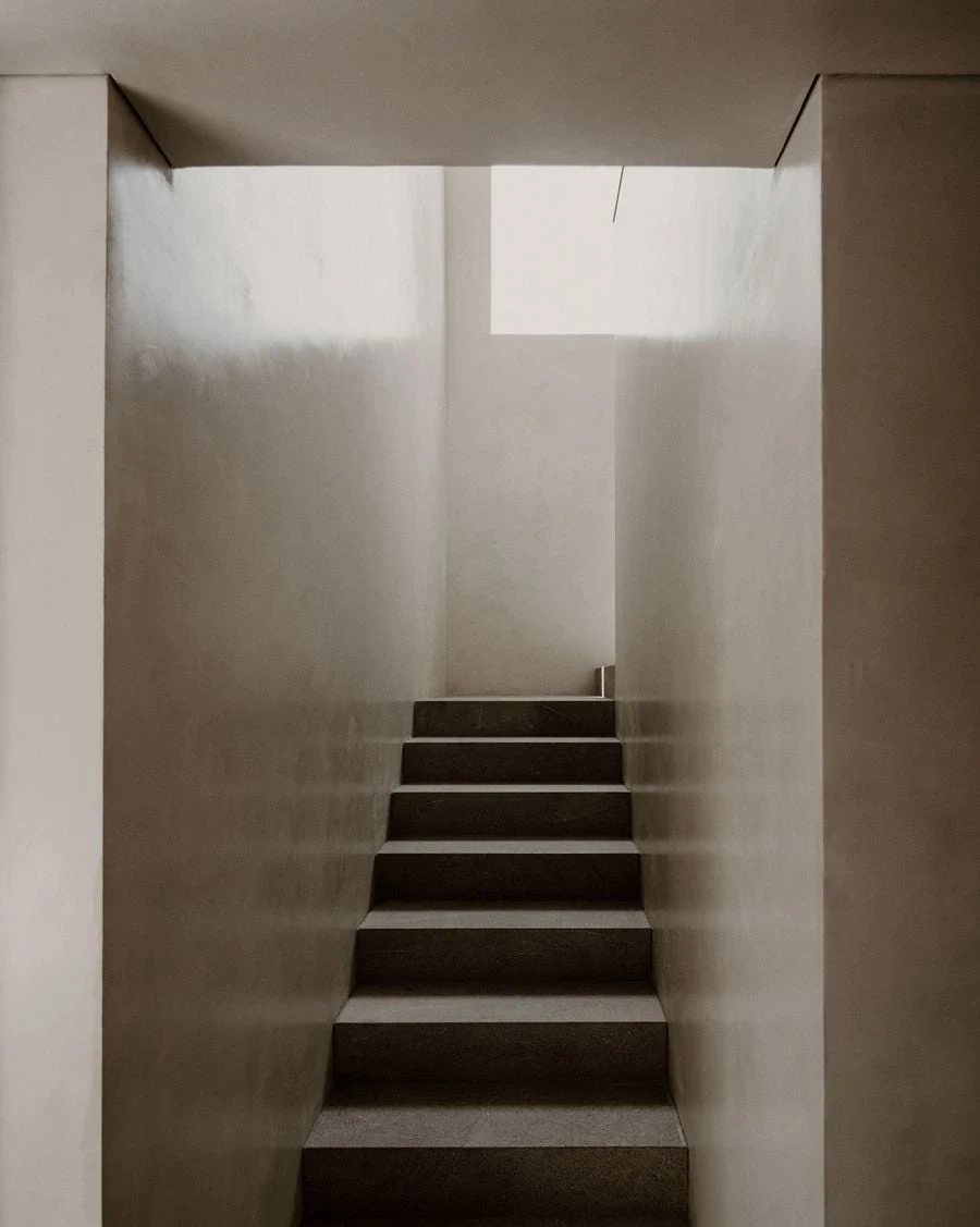 Barrancas by PPAA, photographed by Luis Garvan — a first-floor study with gridded oak shelving filling one wall, a single armchair and a travertine side table its only other furnishing.