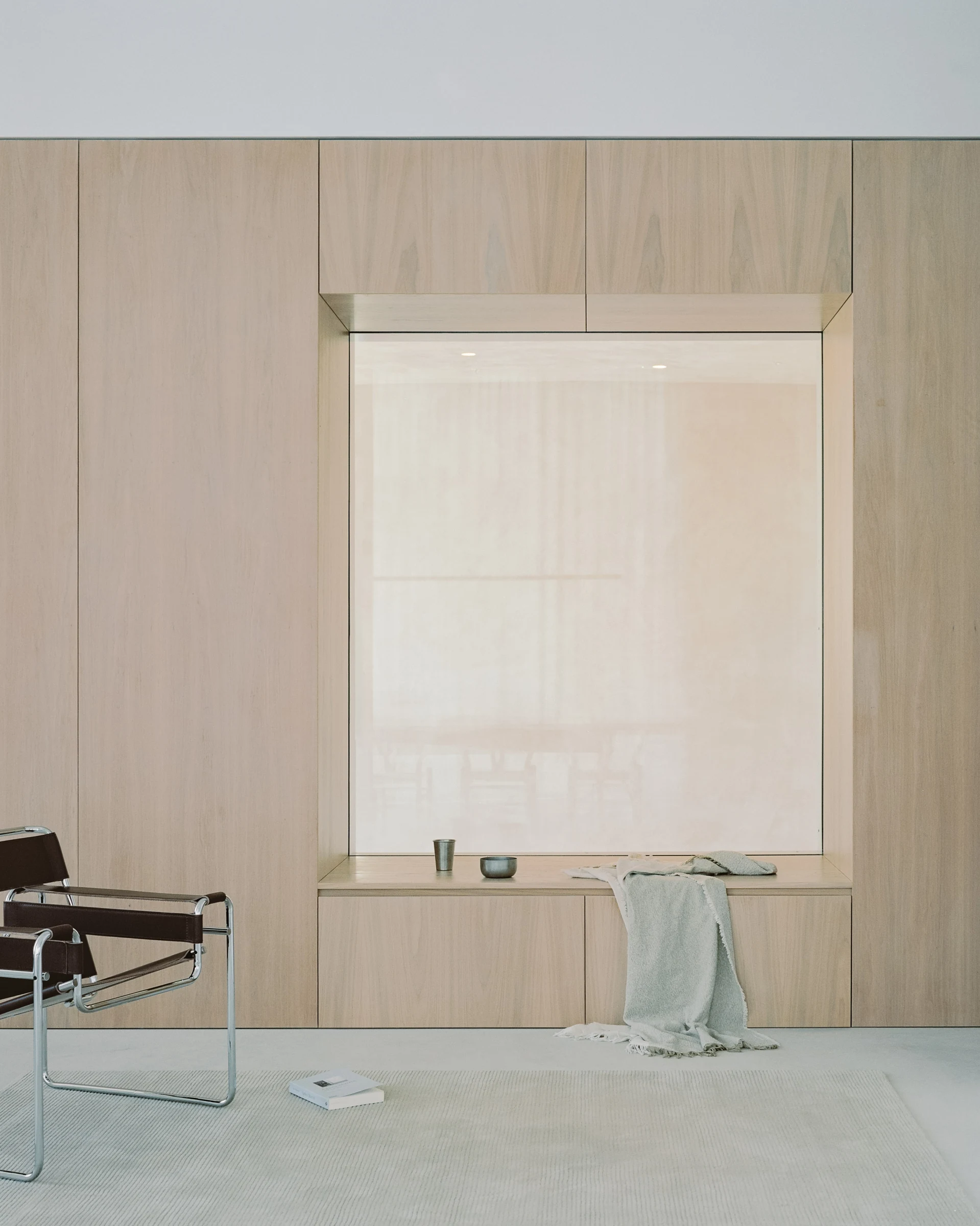Cherry Orchard by Actual Office, photographed by Nick Dearden — Inside a private flat: a corridor lined entirely in white-oiled oak panelling, kitchen joinery visible at the right with a stainless worktop, an open doorway slipping through the wood into…
